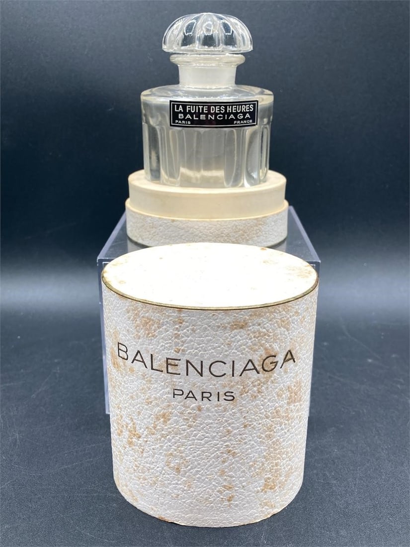 Balenciaga La Fuite Des Heures Perfume Bottle: Balenciaga La fuite de heures perfume bottle with original box. Features lead crystal glass with rounded petal patterned stopper. Bottle is in good condition, box has some stains as noted in photos.Me