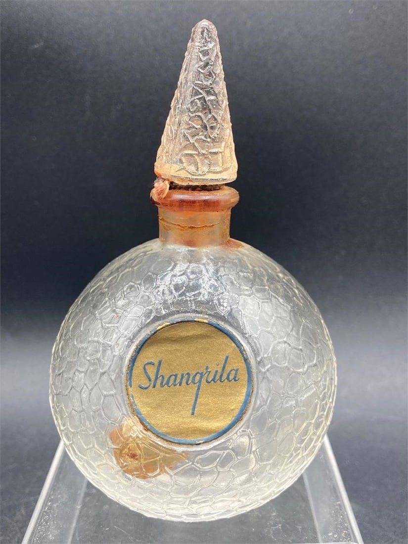 Vintage Shanqrila Pebbled Glass Perfume Bottle: Vintage Shanqrila pebbled glass perfume bottle. Features random pebbled pattern, cone shaped stopper and clean front label. Measures 4" tall. Good condition.Measurements: 3" W, 3" L, 4" H, 1 pound