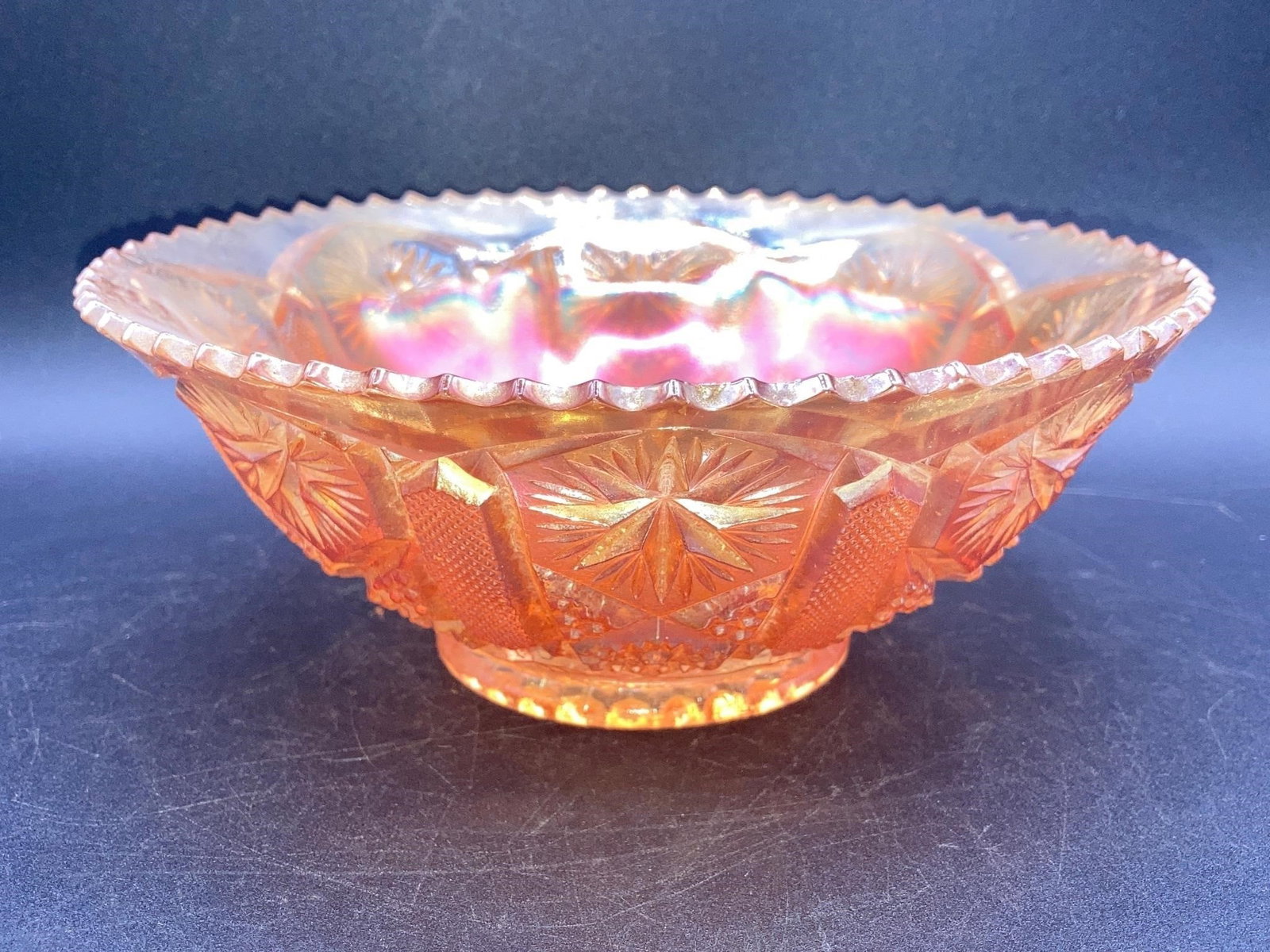 Carnival Glass Marigold Star & File Bowl: Carnival glass iridescent marigold star & file bowl. Features starburst, hobstar and file patterns on glass that changes color under different lighting. Measures 7" across. Bowl is in good condition.M