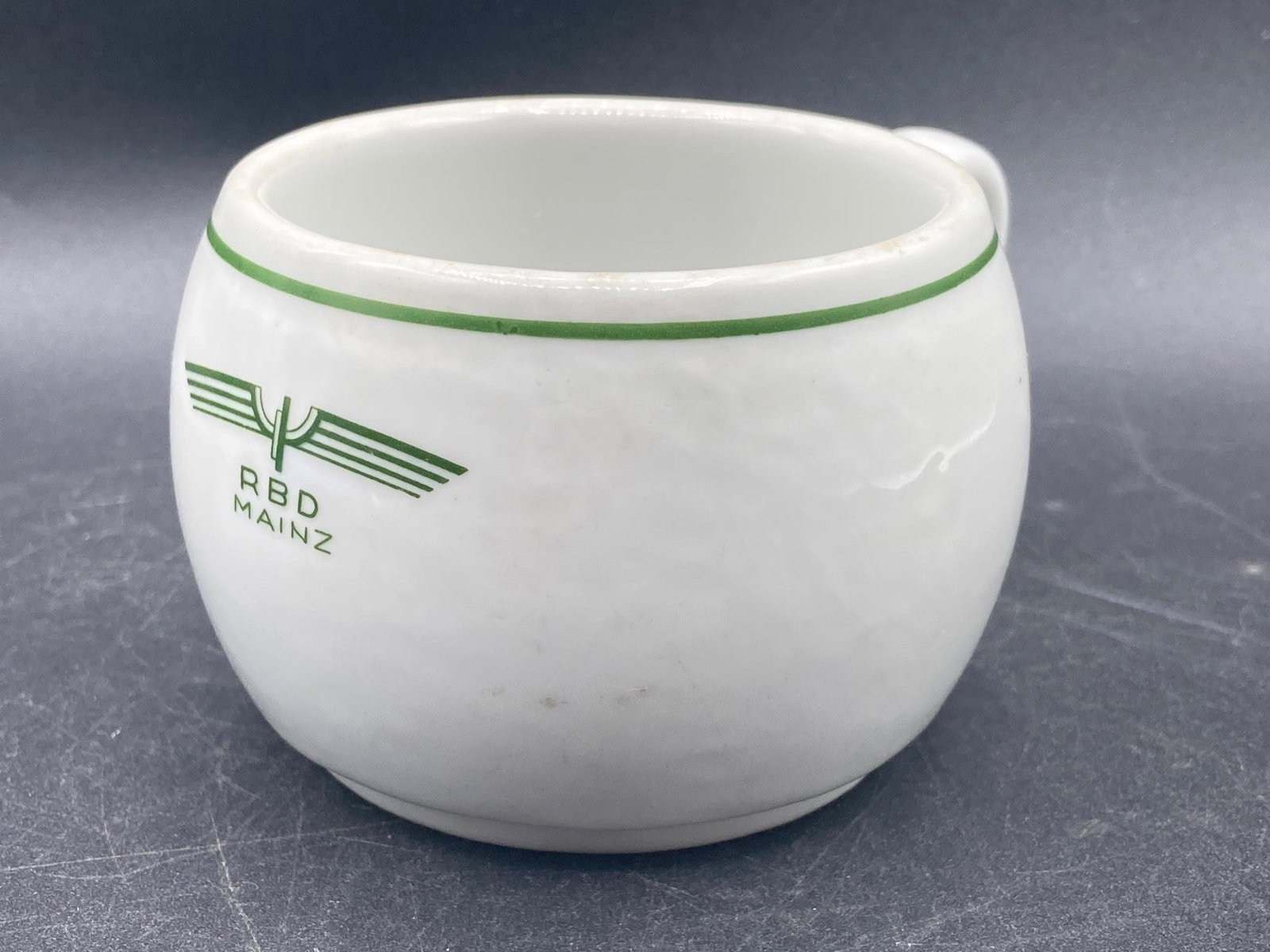 German WWII Deutsche Arbeits Front Coffee Mug: German world war II era Deutsche Arbeits Front porcelain mess hall coffee cup. RBD Mainz stamp on front of cup, Deutsche Arbeits Front maker stamps noted in noted on bottom. One small chip noted on ri