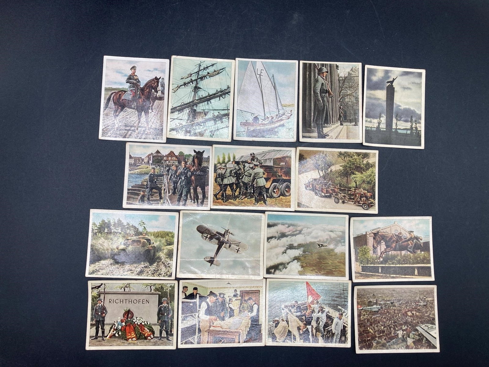 WWII Era German Wehrmacht Cigarette Cards: Set of sixteen 1930s German Wehrmacht cigarette cards. Cards feature color photo prints of soldiers and military scenes of the German army and navy preparing for war. Cards measure 2" wide by 2.5" lon
