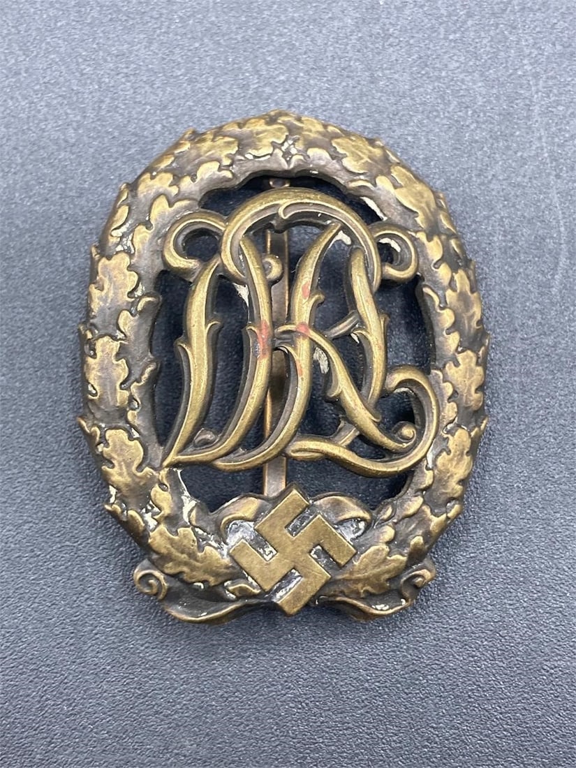 WWII German DRL Sports Badge In Bronze: World War II German DRL sports badge. Bronze badge with Jena Wernstein maker stamps noted on back. Measures 2". Some light tarnishing, overall badge is in excellent condition.Measurements: 2" W, 2" L,