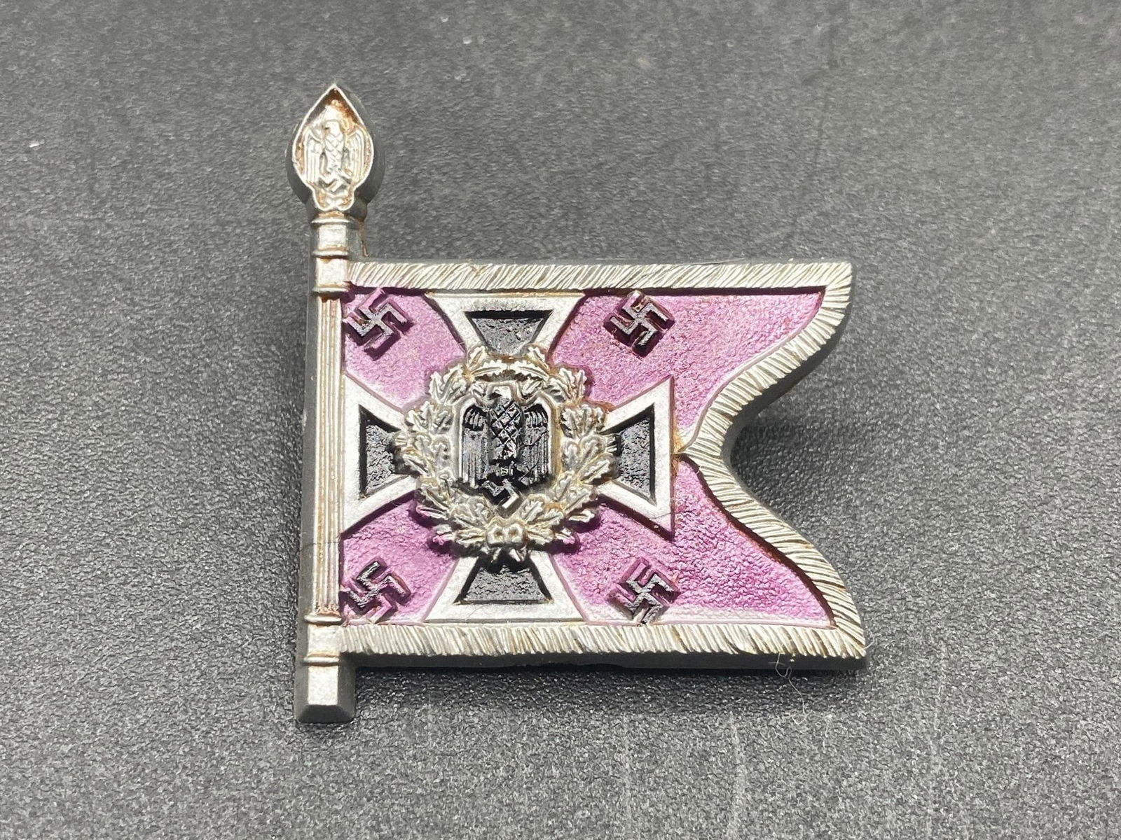 WWII German Luftwaffe Regiment Flag Tinnie: World War II German Luftwaffe regiment flag tinnie. Plastic material with painted front in shape and colors of the regiment flag. "Nebeltruppe SU 15" stamp on back. Measures 1 1/4". Pin is in excellen