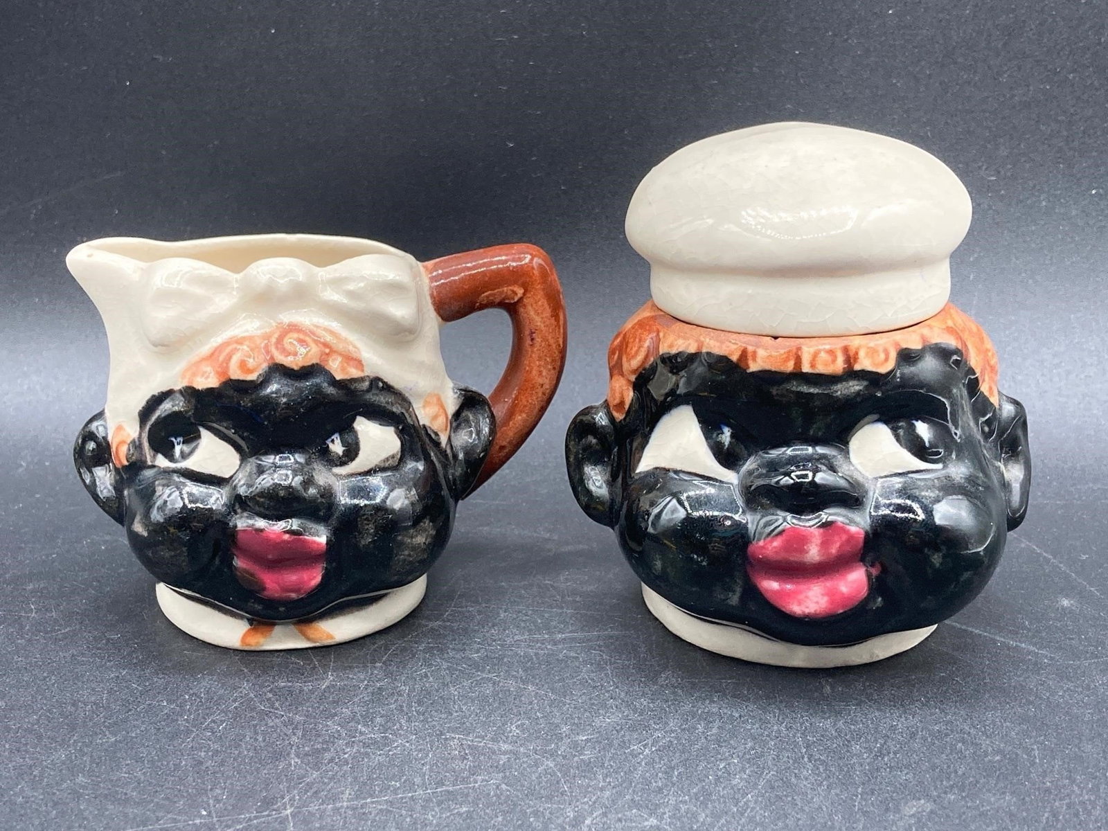 Black Americana Porcelain Creamer & Sugar Bowl: Vintage black Americana porcelain creamer and sugar bowl. Circa 1950s. Hand painted in the designs of the era. Natural crackling visible under glaze. Measures 3" tall each. Set is in excellent conditi