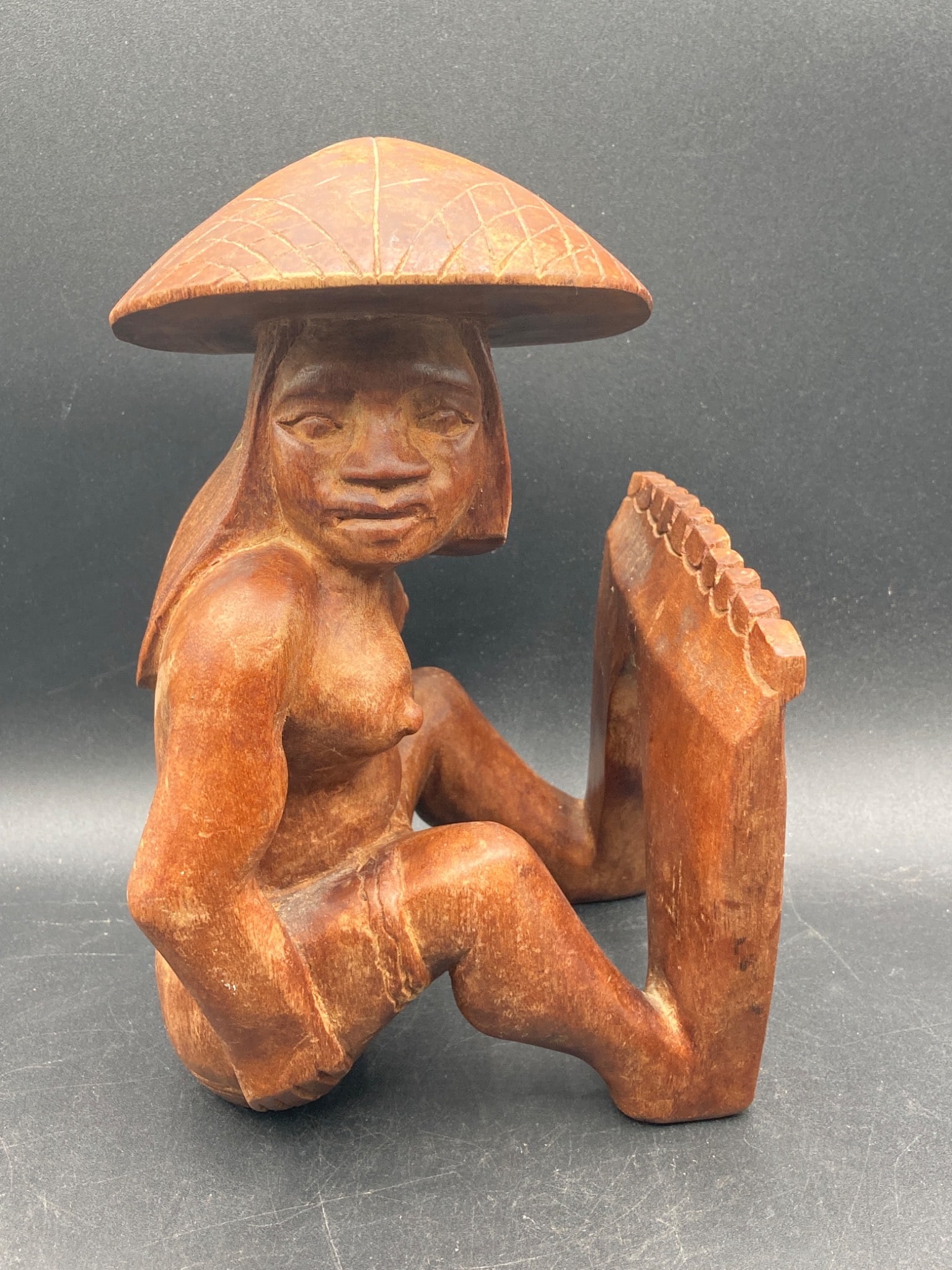 Philippines Wooden Nude Woman Book End: This is a hand-carved wooden sculpture originating from the Philippines, featuring a nude woman in a seated pose with a traditional hat. The piece serves as a functional bookend and exhibits detailed