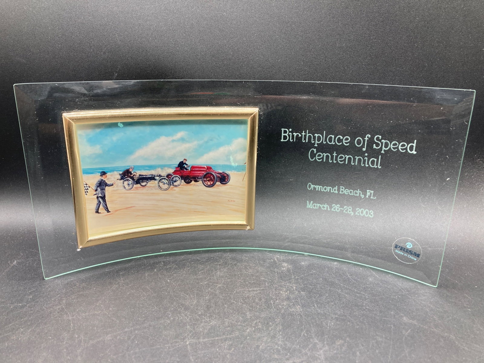 Ormond Beach Birthplace of Speed Centennial Plaque: This is a commemorative glass display plaque from the Birthplace of Speed Centennial celebration, which took place at Ormond Beach, Florida, from March 26 to March 28, 2003. The curved glass plaque fe