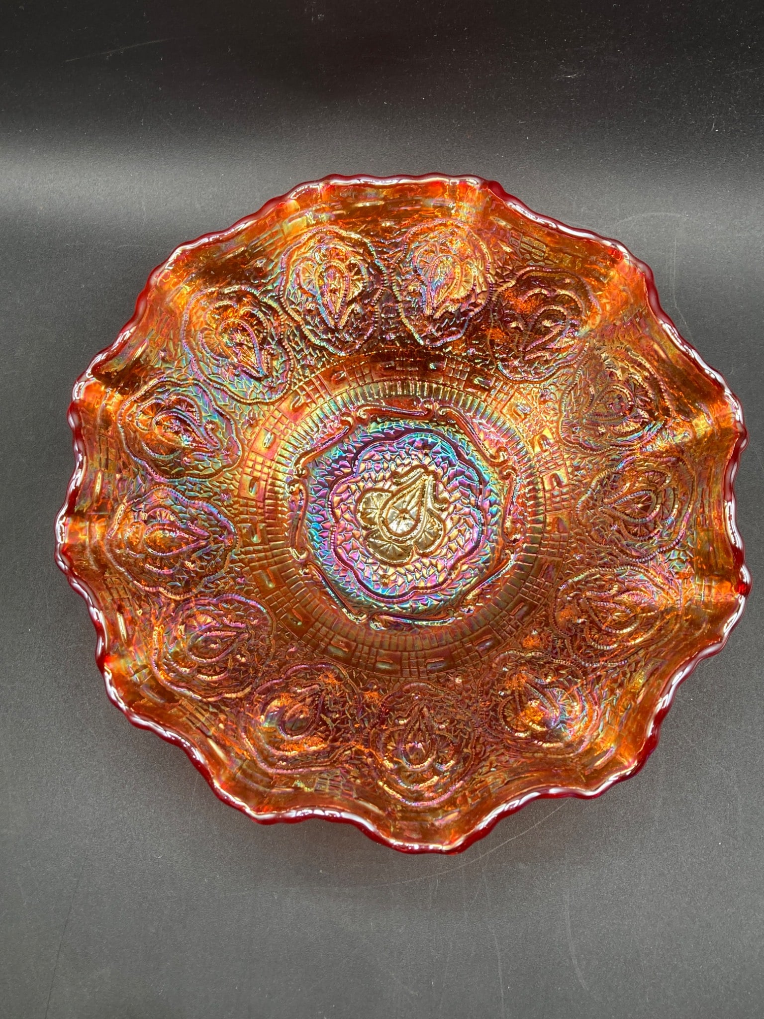 Fenton Marigold Carnival Glass Bowl: This is a Fenton glass marigold carnival glass bowl. The bowl features an iridescent marigold finish with an intricate raised floral and geometric pattern throughout. It has a crimped edge design and 
