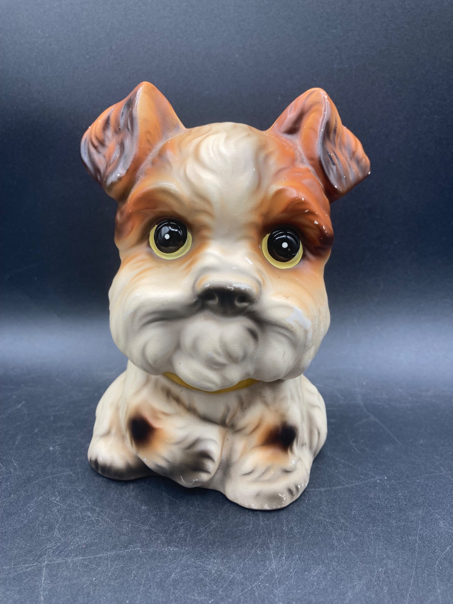 Norleans Japan Scottie Dog Coin Bank Ceramic Figurine: This is a vintage Scottie dog ceramic coin bank made in Japan by Norleans. The figurine is hand-painted and features a slot on the back for inserting coins. The piece has a yellow collar detail and is