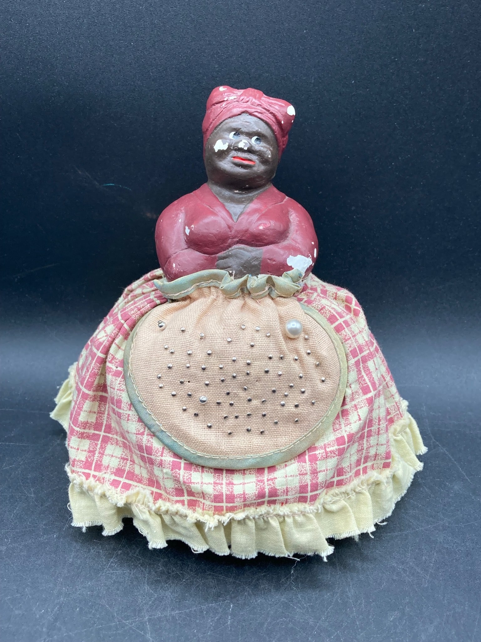 Black Americana Mammy Chalkware Pincushion Figurine: This is a chalkware pincushion figurine often referred to as 'mammy' in Black Americana collectibles. The figurine features a painted chalkware body with noticeable paint chipping and wear. It include