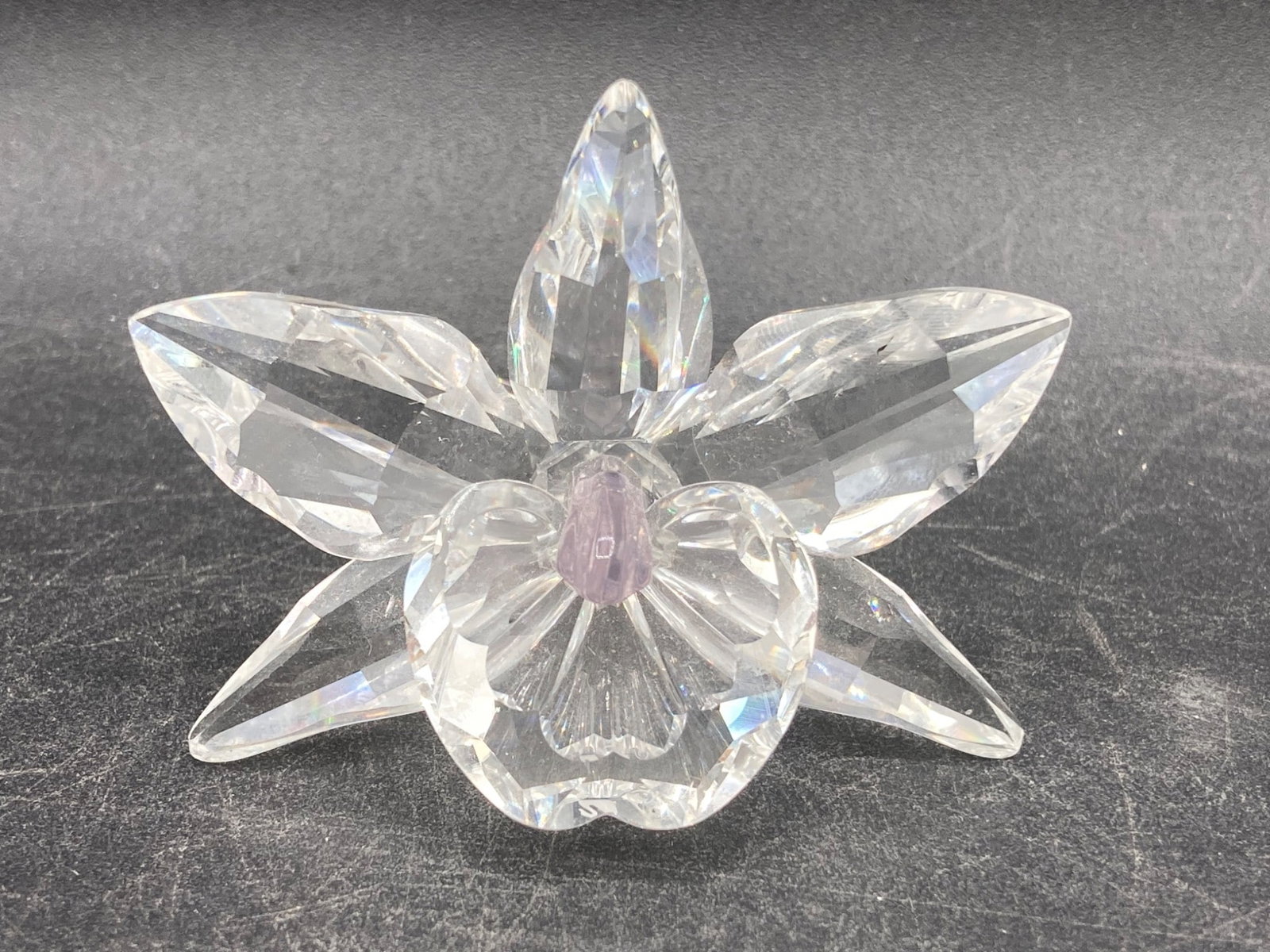 Swarovski Pink Orchid Crystal Figurine: This is a Swarovski pink orchid crystal figurine, finely crafted using clear Swarovski crystal for its petals and stem, with a subtle pink center accent. The piece is reflective and showcases high cra