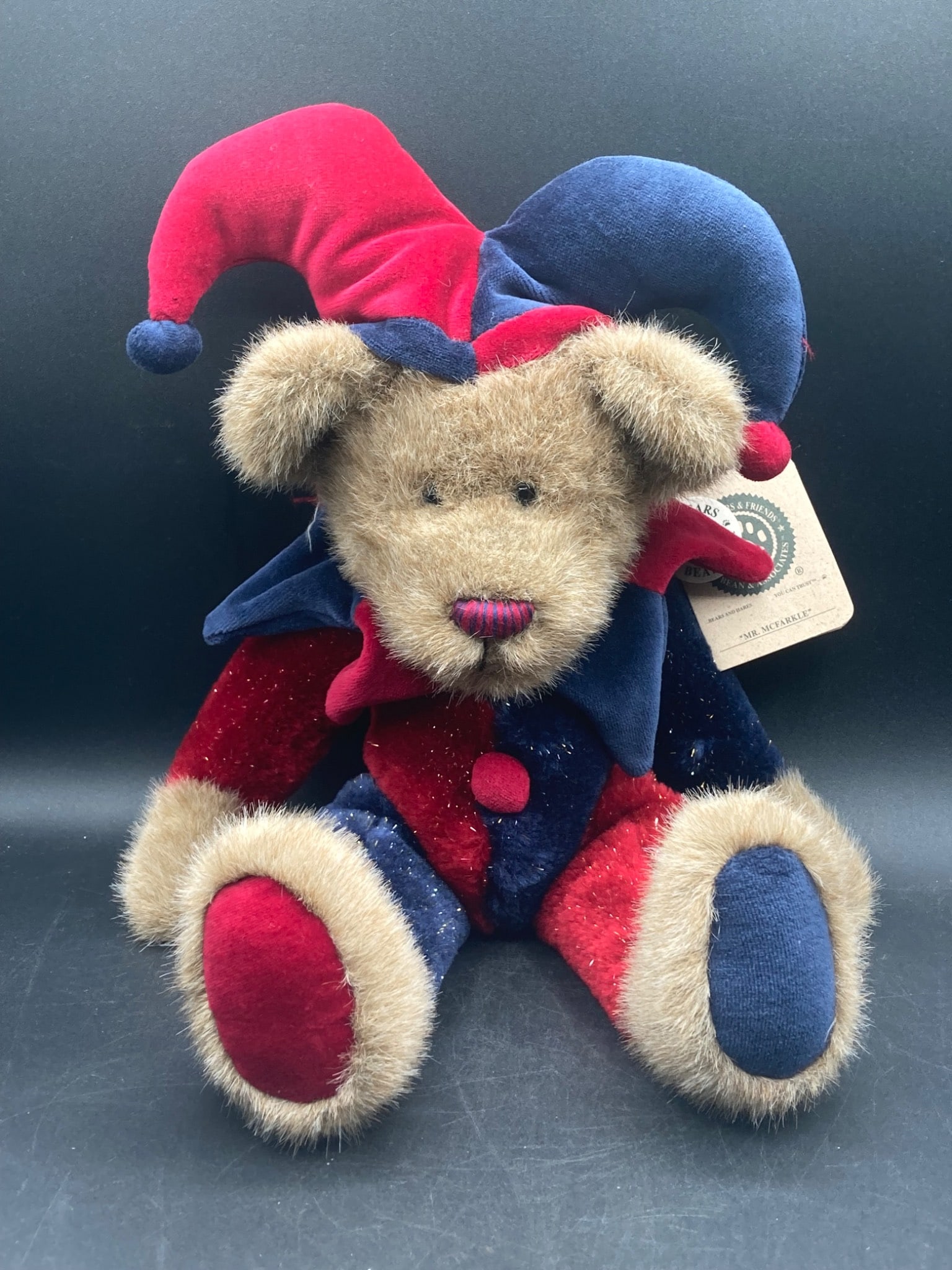 Boyds Bears Mr. McFarkle Bear: This is a plush collectible bear from Boyds Bears, model Mr. McFarkle. It features a red and blue jester outfit with metallic accents. This item includes its original hang tag, verifying its authentic