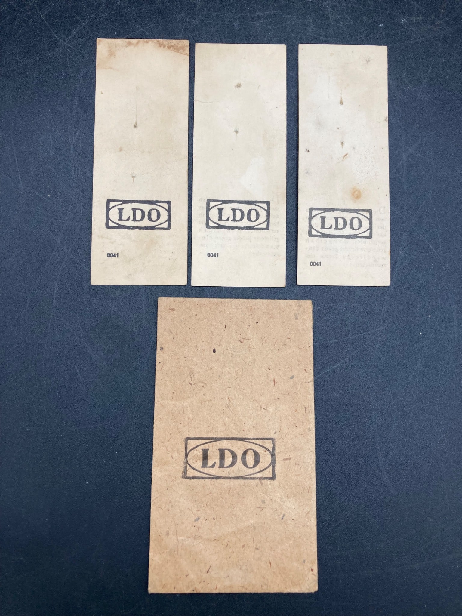 WWII German LDO Packet With Pin Slips: This lot includes a WWII German LDO packet and three accompanying pin slips. The packet and slips display the "LDO" logo and German manufacturer text, indicating compliance with regulations during the