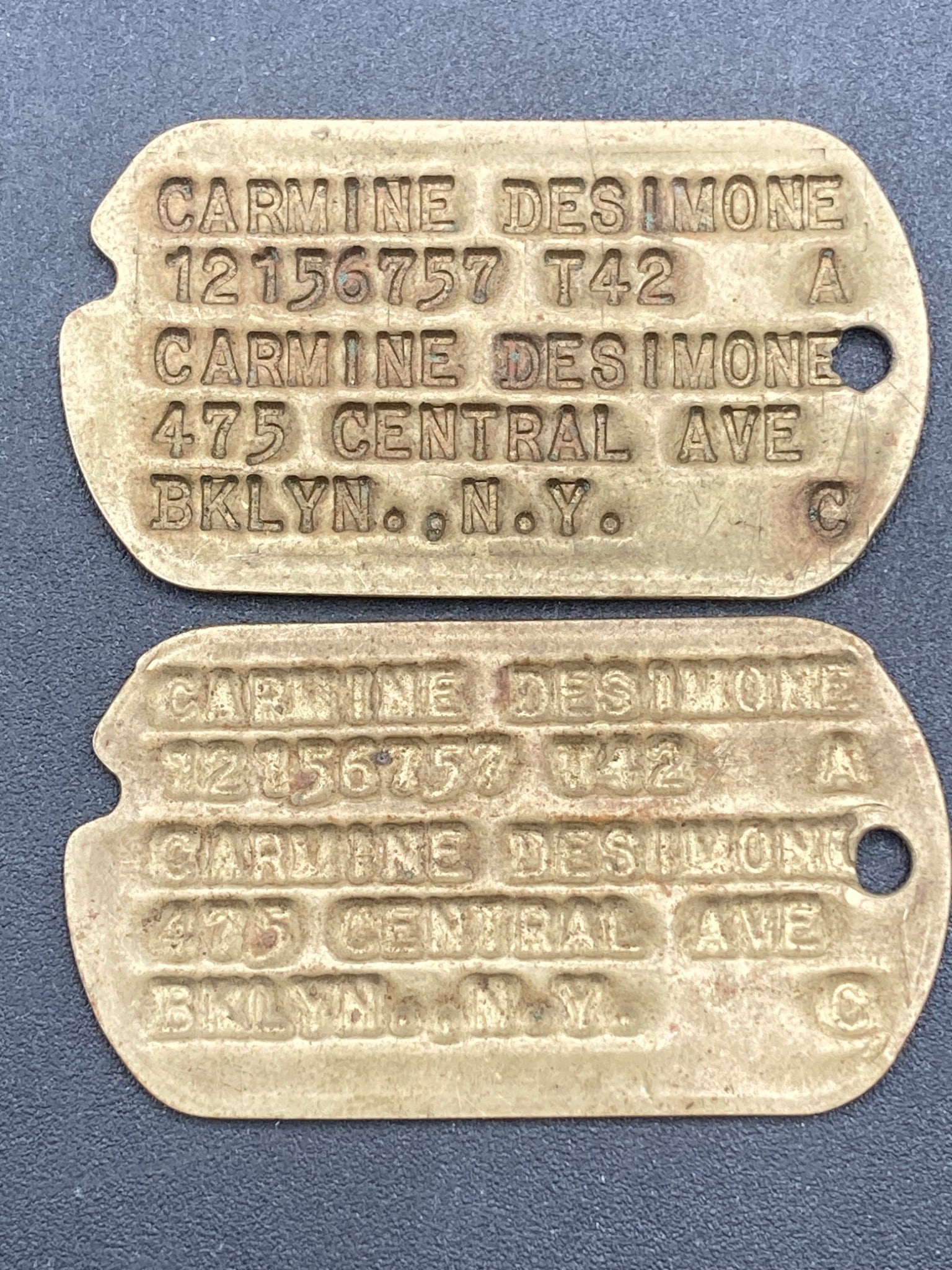 WWII United States Army Dog Tags: Set of WWII-era United States Army dog tags belonging to Carmine Desimone. Features stamped identification details, including name, service number 12156757, blood type A, T42 tetanus vaccination year