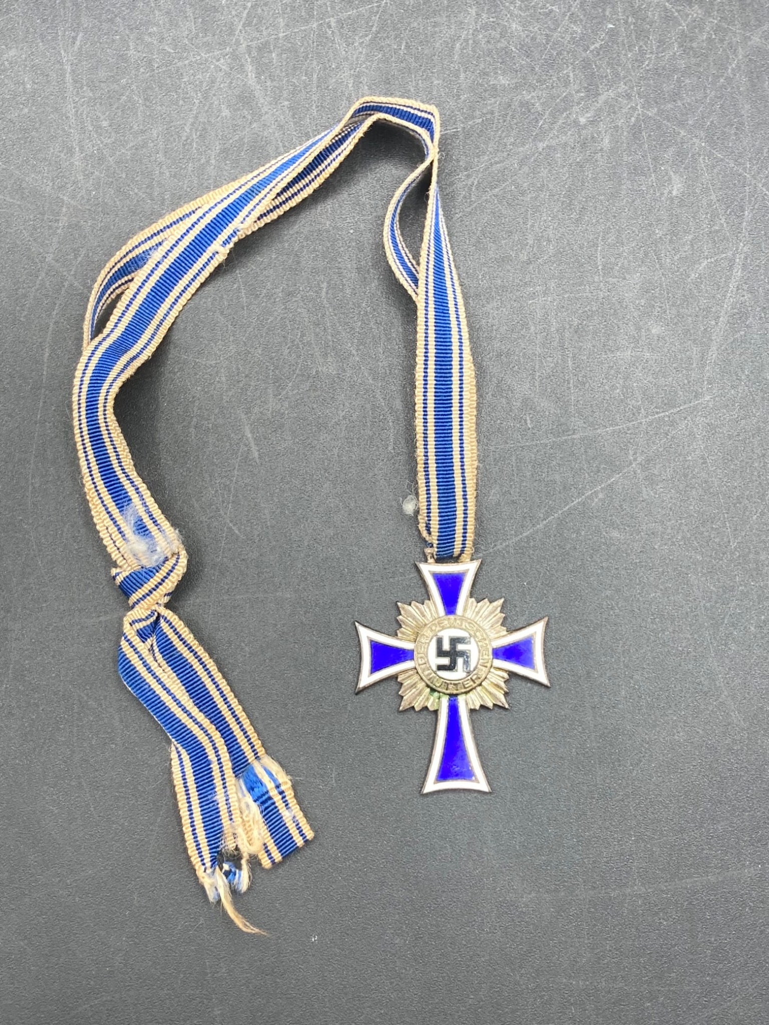 WWII German Mother’s Silver Cross with Ribbon: This lot includes an authentic WWII German Mother’s Silver Cross, featuring a blue enamel design with silver accents. The reverse side is engraved with '16 Dezember 1938' and a facsimile of Adolf Hi