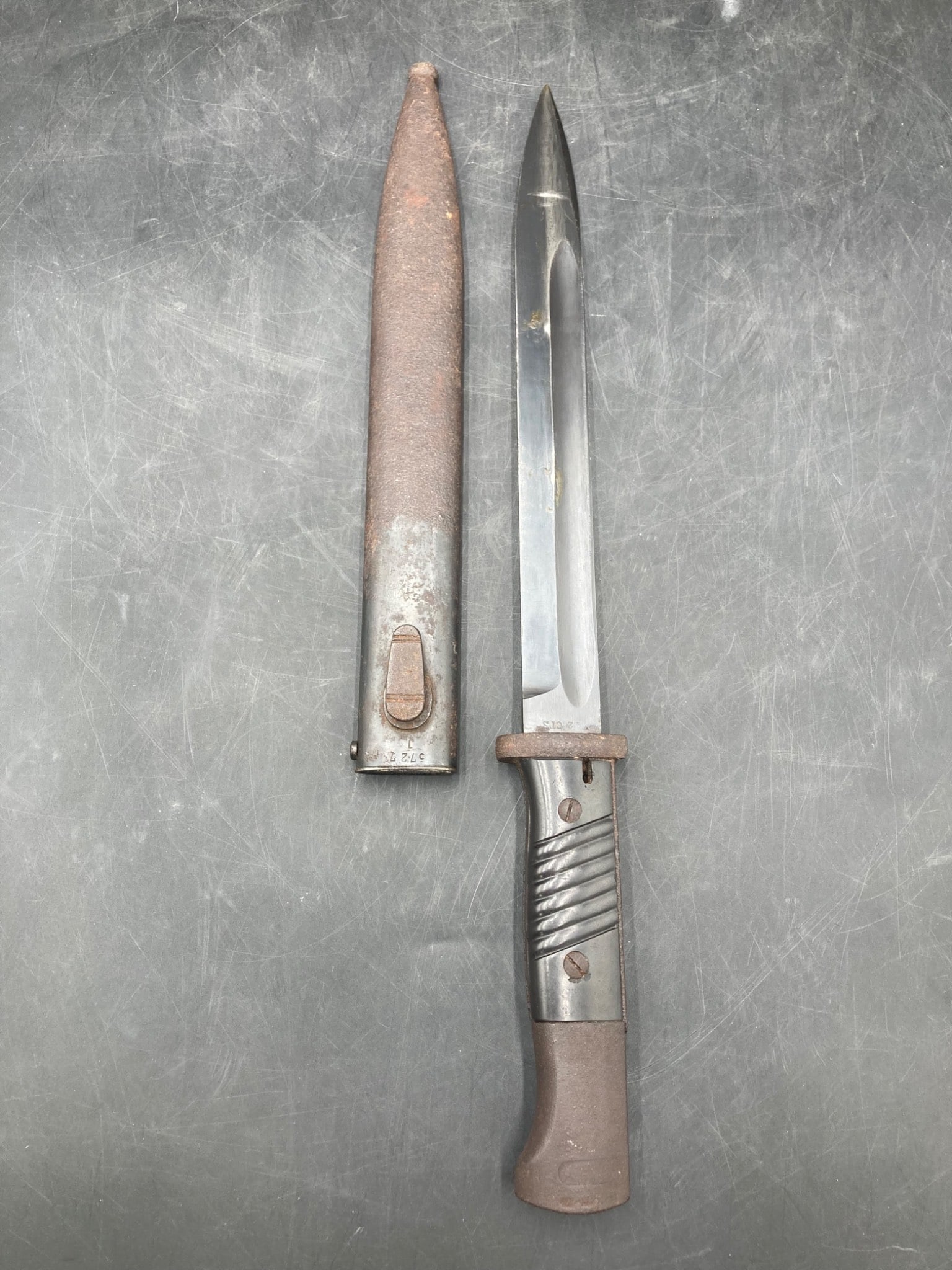 Original WWII German Bayonet with Scabbard: This is an authentic WWII-era German bayonet with its matching scabbard. The bayonet shows serial numbers on both the blade and scabbard, including and '5727 J,' and a maker stamp of F.W. Holler indic