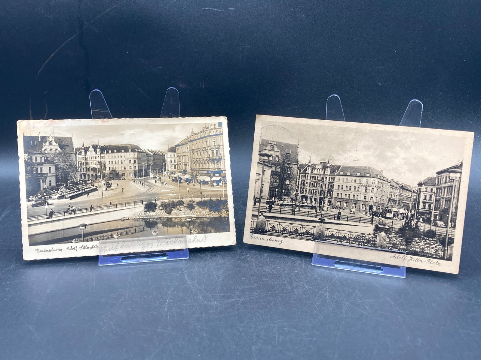 Set of WWII German Postcards: This lot includes two WWII-era German postcards featuring Adolf-Hitler-Platz in Braunschweig. Both display sepia-toned imagery with handwritten text and postal markings on the reverse side, including 