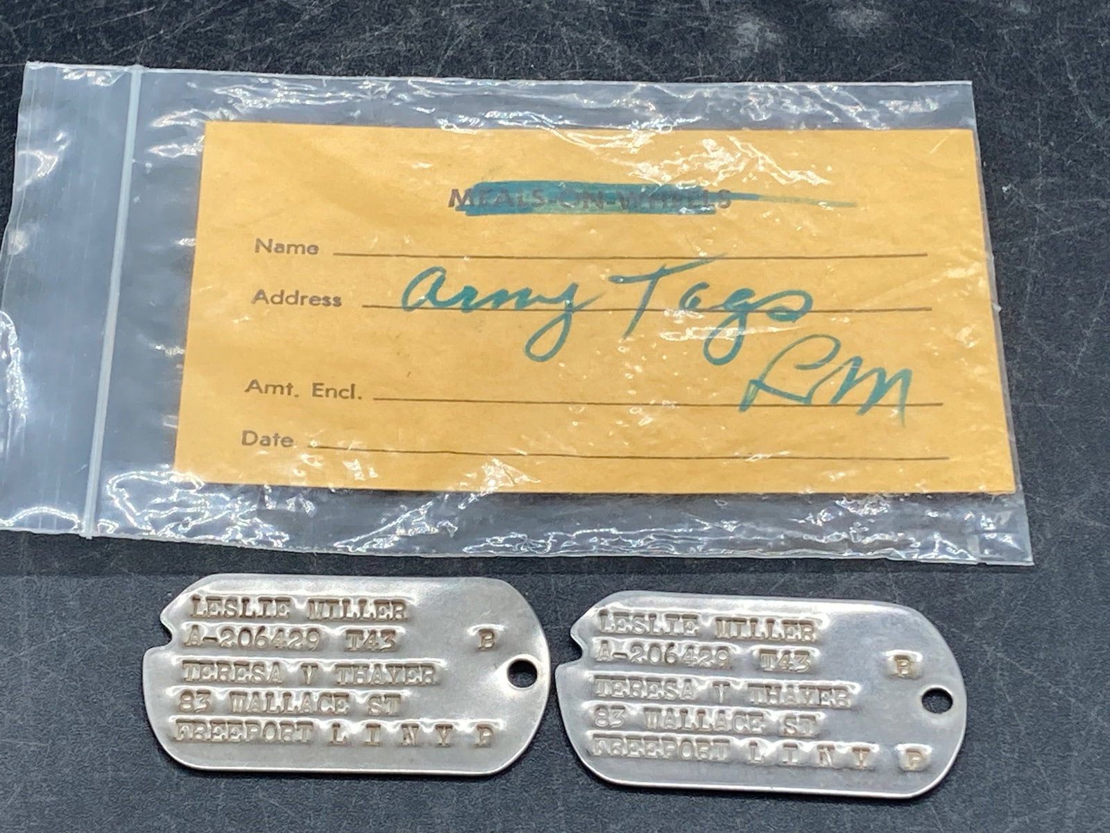 WWII United States Army Dog Tags with Pouch: A pair of original World War II-era United States Army dog tags belonging to 'Leslie Miller,' featuring stamped details such as name, serial number (A-206429 T43), blood type (B), and next of kin ('Te