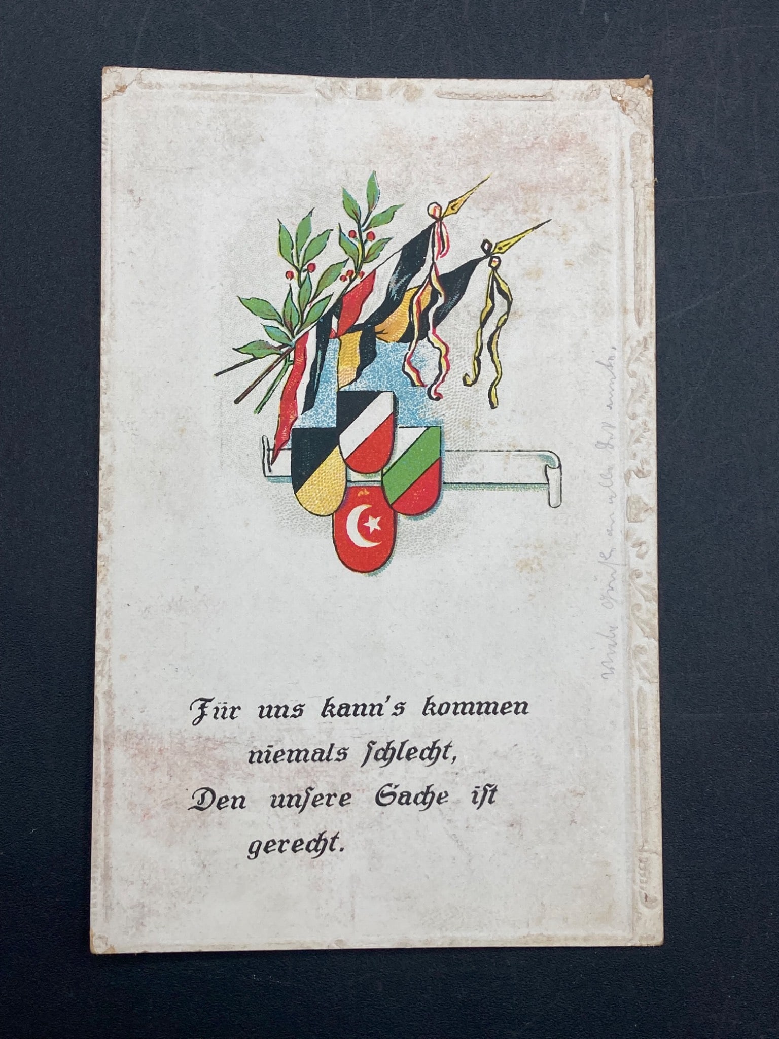 WWI Era Imperial German Postcard: This postcard originates from the WWI era, as indicated by the postmark dated 8.1.18. It features an illustration of multinational flags and banners with accompanying text in German: 'Für uns kann's