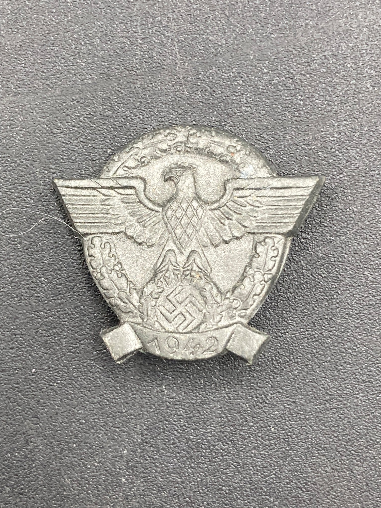WWII German Police Supporter Tinnie, 1942: This WWII-era German Police Supporter Tinnie features a prominent eagle emblem above a swastika, surrounded by a laurel wreath design. The piece is dated 1942 on the front. The reverse side includes a