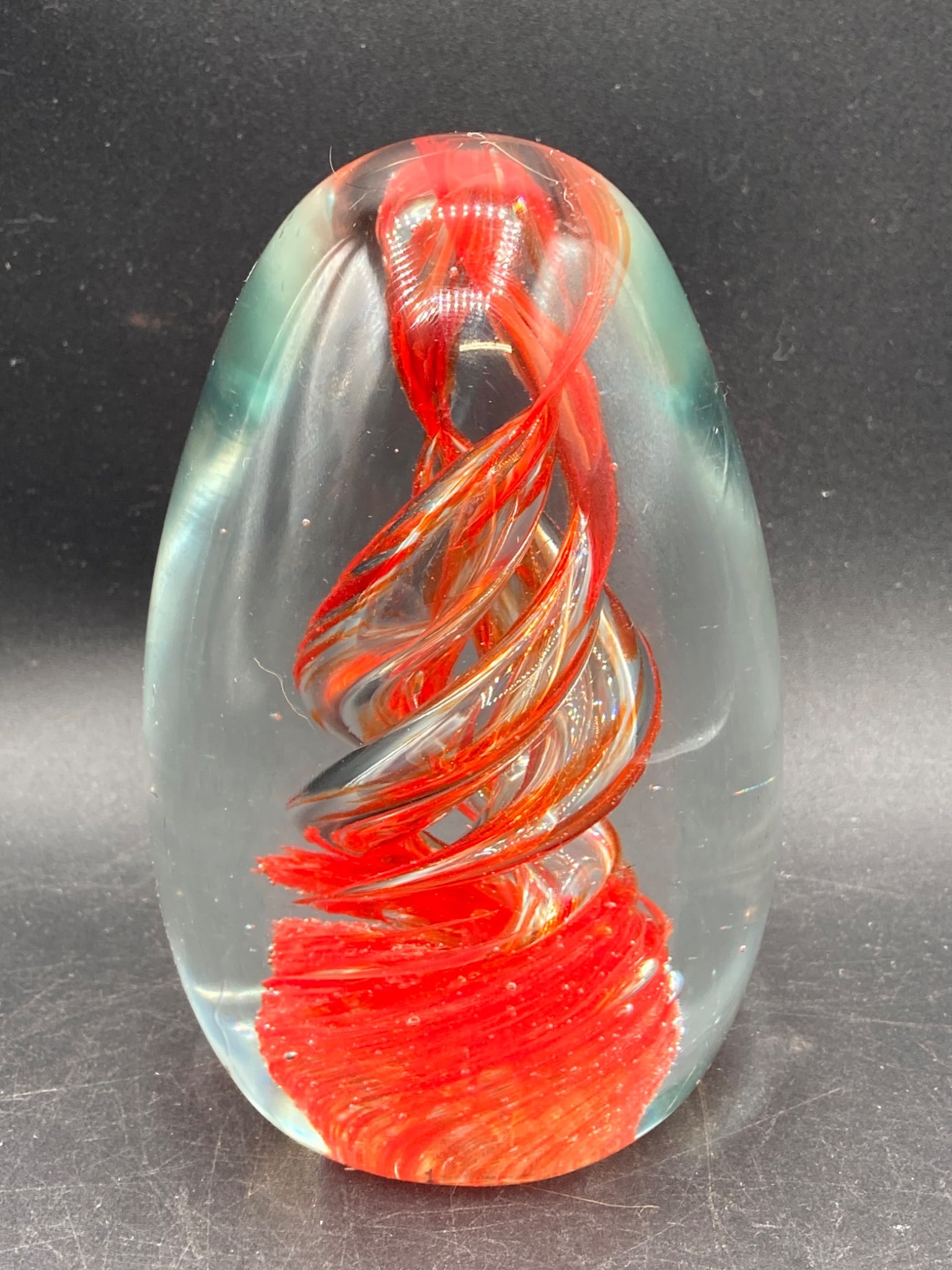 Red Swirl Murano Glass Paperweight: This is a Murano glass paperweight, crafted in Italy, featuring an elegant swirling red and gold ribbon design encased in clear glass. The piece is labeled with 'Italy Design' on the base and measures