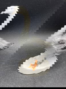 German Porcelain Goose Figurine: This is a porcelain figurine in the shape of a goose, with detailed painting on its body and orange feet. The piece is marked 'Germany' on the underside of the base. The figurine measures