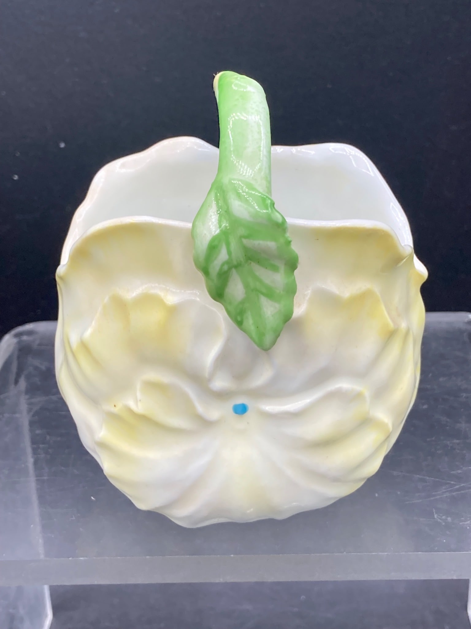 Porcelain Floral Pattern Miniature Basket: This porcelain miniature basket features a floral-inspired design with yellow and white hues and a green handle crafted in a leaf motif. The basket measures approximately 3.5 inches in height. A small