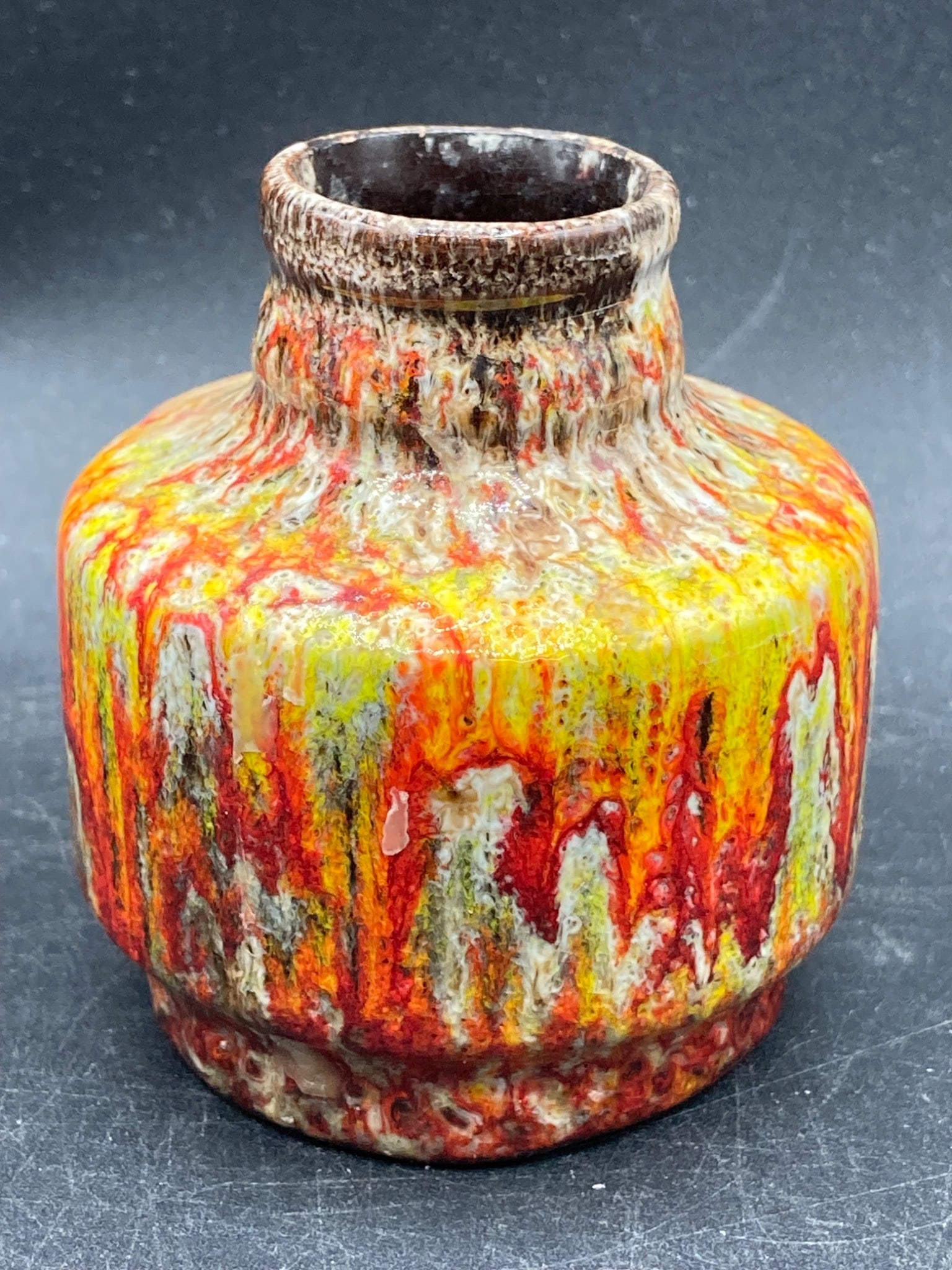 Miniature Drip Glaze Clay Pot: This miniature clay pot features a vibrant multicolor drip glaze in hues of red, yellow, and white. Standing approximately 3 inches tall, the pot has a smooth, unglazed terracotta base showing its han
