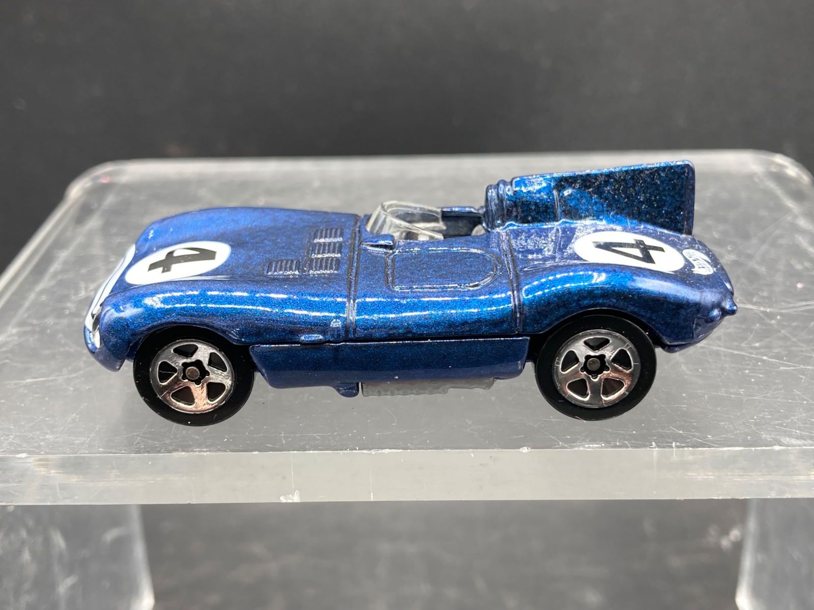 Hot Wheels 1/64 Scale Jaguar D-Type Die-Cast Model Car: This is a 1/64 scale die-cast model of the Jaguar D-Type produced by Hot Wheels. The model features a metallic blue finish with the number '4' decals on the hood and sides. It includes detailed bodywo