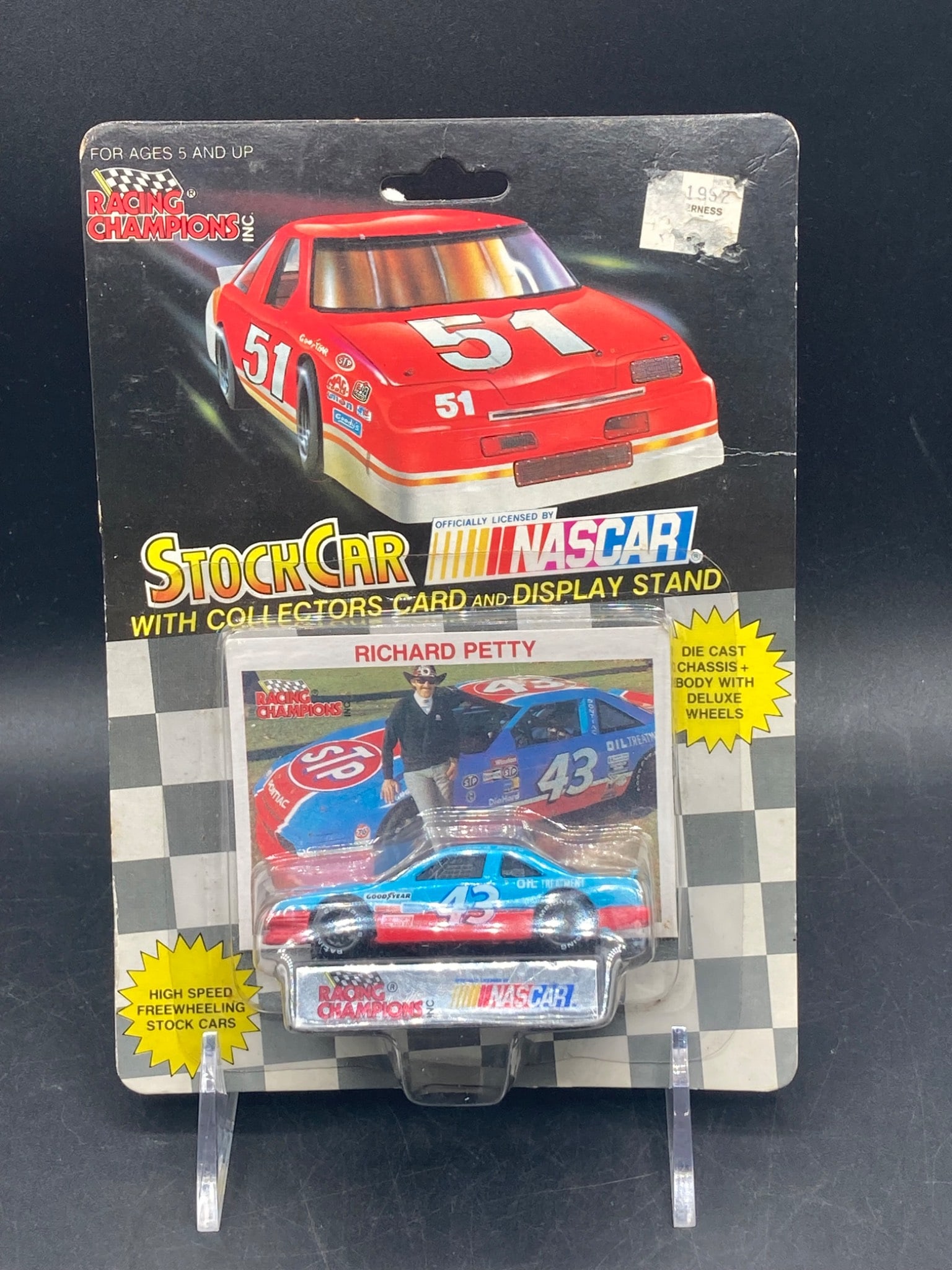 Racing Champions 1:64 NASCAR Stock Car No. 43 Richard Petty Die Cast: This is a Racing Champions 1:64 scale NASCAR Stock Car Model No. 43, featuring Richard Petty. The packaging includes a die-cast car with chassis and deluxe wheels, a collector's card, and a display st