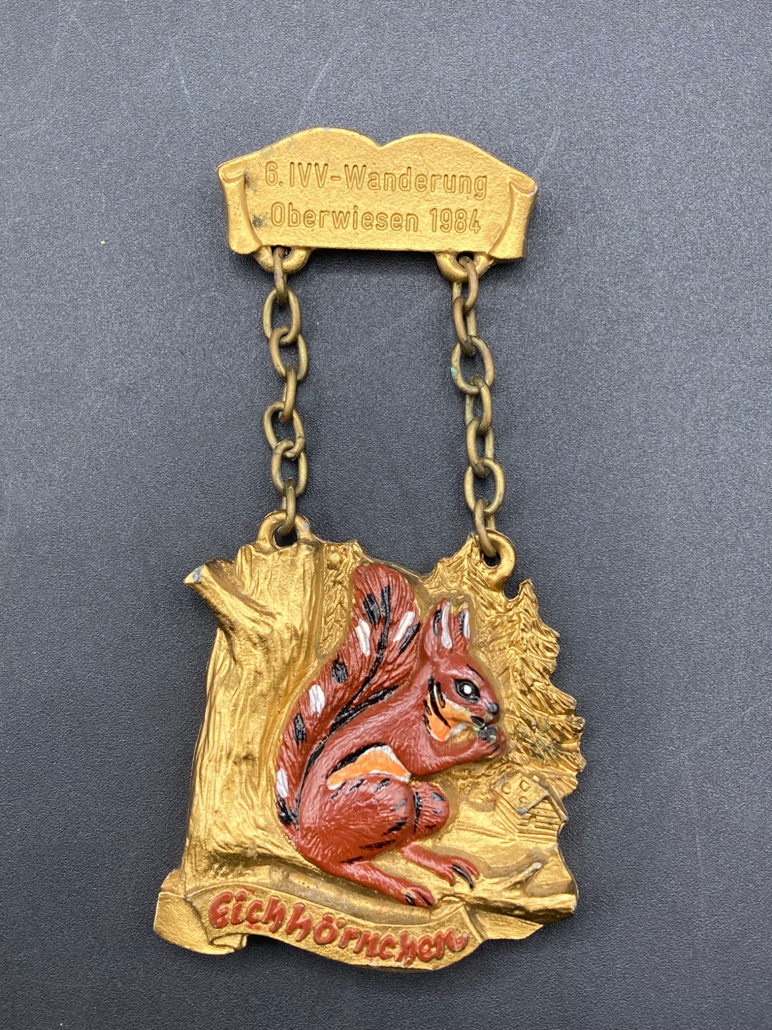 1984 6. Wanderung Oberwiesen Medal with Eichhornchen Squirrel Design: Commemorative medal from the 6th IVV Wanderung event held in Oberwiesen in 1984. Features a squirrel ('Eichhornchen') design, rendered in painted relief on a gold-tone surface. Includes a chain attach