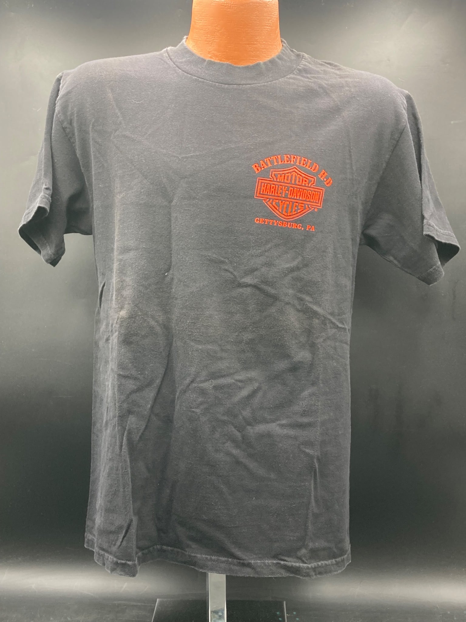 Battlefield Harley-Davidson Grand Opening T-Shirt, Gettysburg PA, Size M: This is a Battlefield Harley-Davidson Grand Opening t-shirt from Gettysburg, PA. Made from 100% pre-shrunk cotton, this black t-shirt features the iconic Harley-Davidson logos on both the front and ba