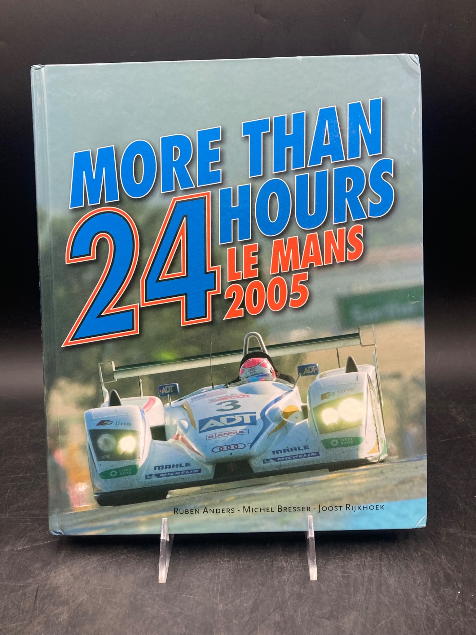 More Than 24 Hours Le Mans 2005 Hardcover Book: This is a hardcover book titled 'More Than 24 Hours Le Mans 2005.' It features photography by Ruben Anders, Michel Bresser, and Joost Rijkhoek, with text by Malcolm Cracknell. The book documents the 2