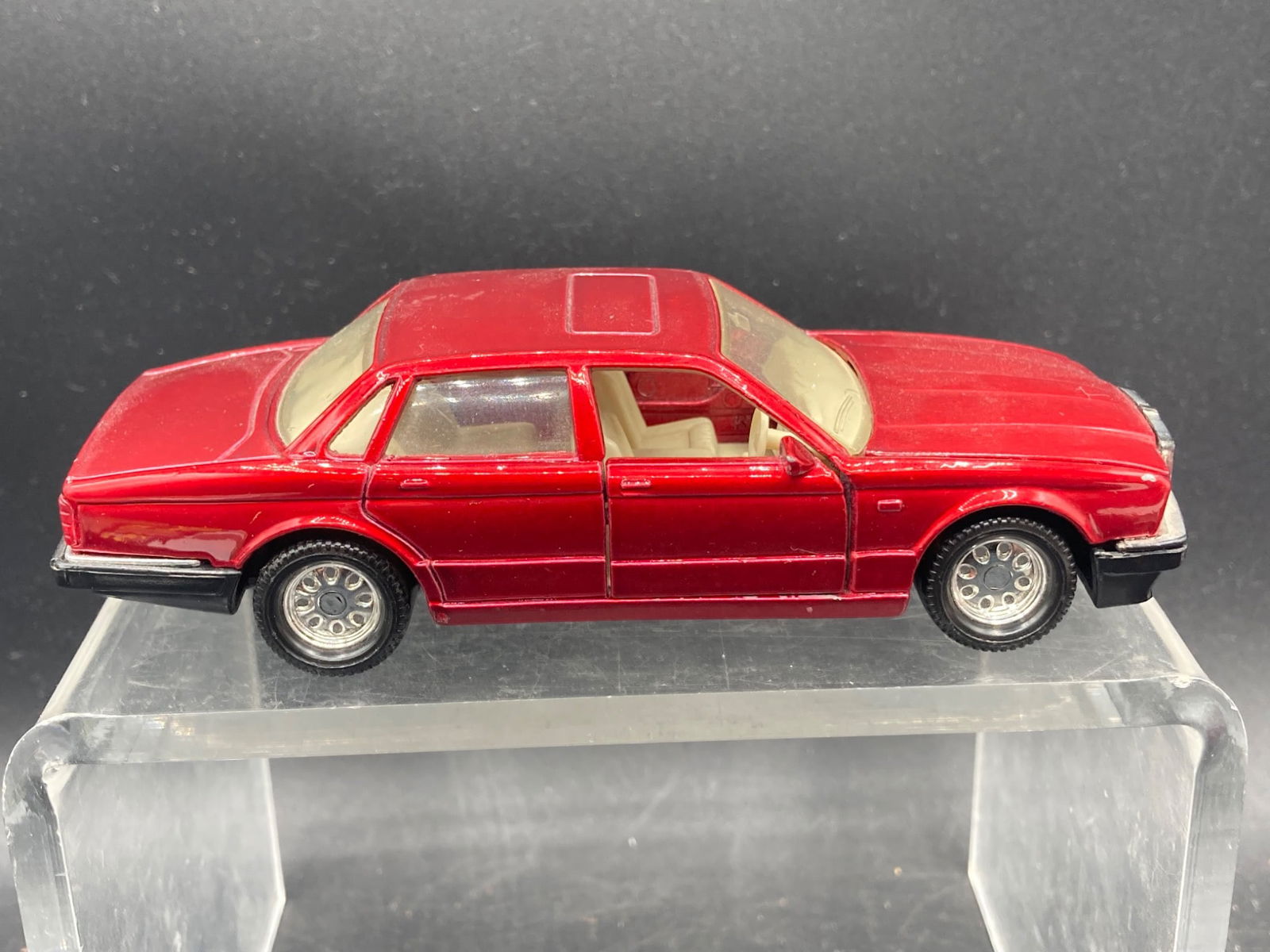 Matchbox Super Kings 1/34 1987 Jaguar XJ6 Die-Cast Model: This is a Matchbox Super Kings Jaguar XJ6 die-cast car model, produced in 1987. The model is 1/34 scale and features a red exterior with beige interior details. Functional elements include opening fro