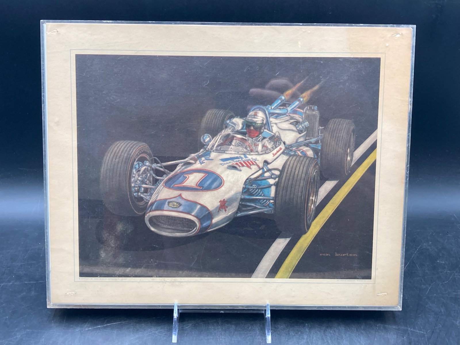 1967 Ron Burton Mario Andretti Racing Print: A racing print by Ron Burton depicting Mario Andretti in a race car, copyrighted 1967 by Jerry Kendrick, Indianapolis, Indiana. The piece features vivid colors and detailed artistry. 'Ron Burton' sign