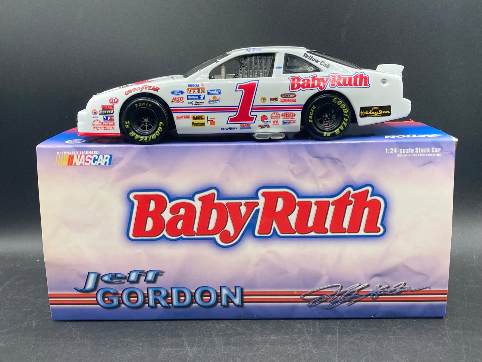 Action Racing 1/24 Jeff Gordon Baby Ruth NASCAR Die-Cast Model: This is a 1/24 scale NASCAR die-cast model by Action Racing, featuring Jeff Gordon's 1992 Ford Thunderbird Baby Ruth #1 race car. The car is detailed with authentic sponsor decals and a Ford logo on t