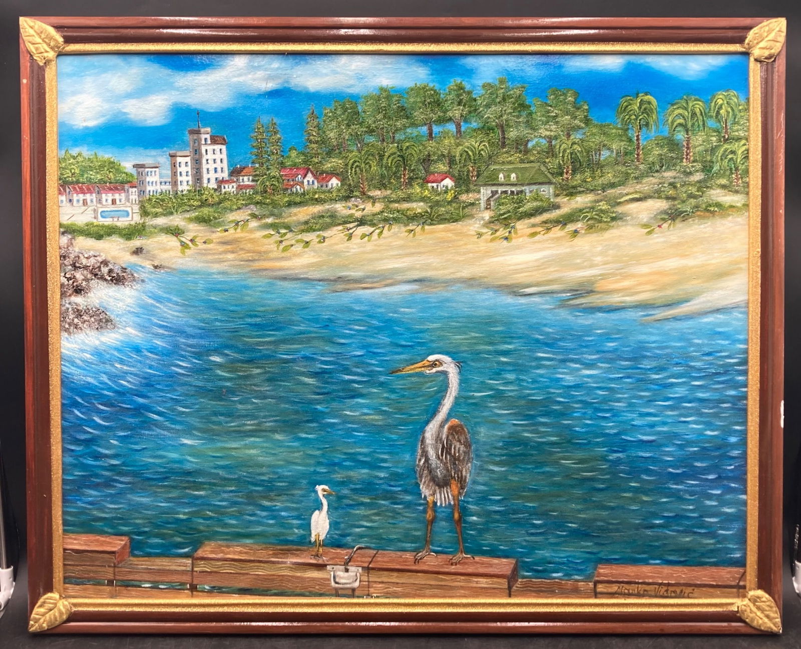 Original Marko Vidovic Beach Landscape Painting: This is an original acrylic painting by Marko Vidovic depicting a coastal landscape with herons on a dock, trees, and buildings in the background. The painting is signed by the artist in the lower rig