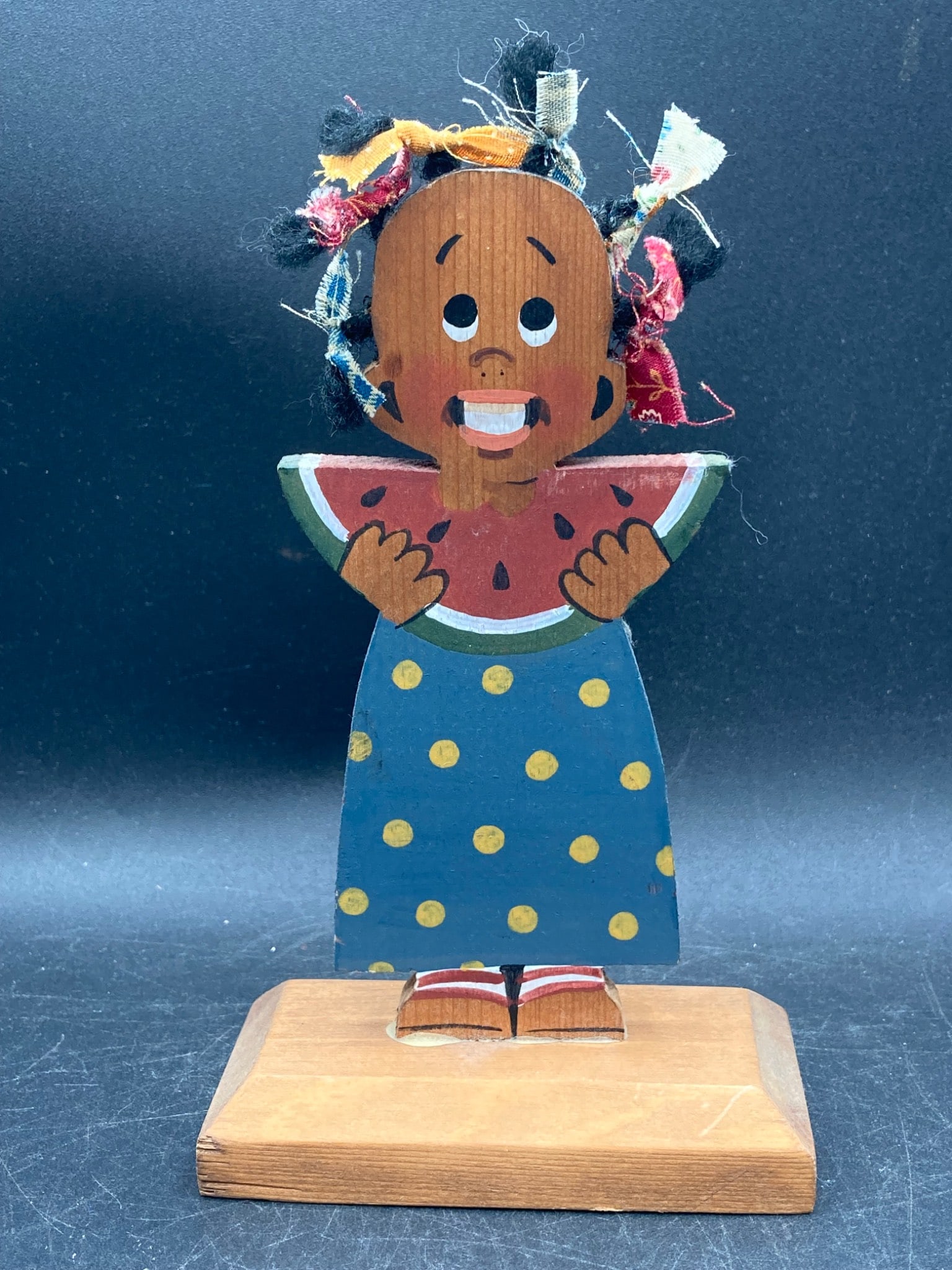 Signed Black Americana Wood Recipe Holder – ‘Lizzy’ 1987: Signed Black Americana wooden recipe holder labeled 'Lizzy' on the back, dated 1987. Features a painted figure holding a watermelon slice with fabric details for hair. Item measures approximately 7 in
