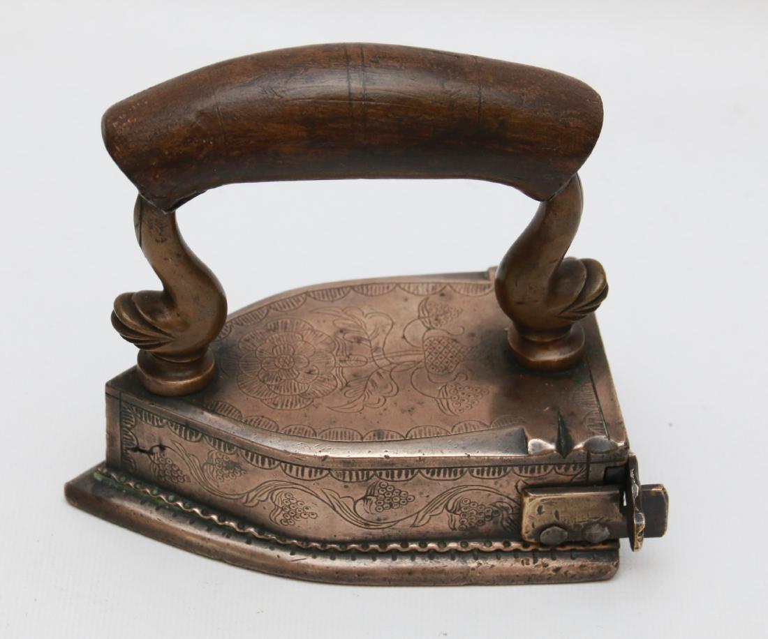 SMALL BRASS SLUG IRON: HIGHLY DECORATED WITH FLOWERS ON TOP AND SIDES - STYLIZED DOLPHIN POSTS - EXTENDING SCALLOP SOLE . 5"