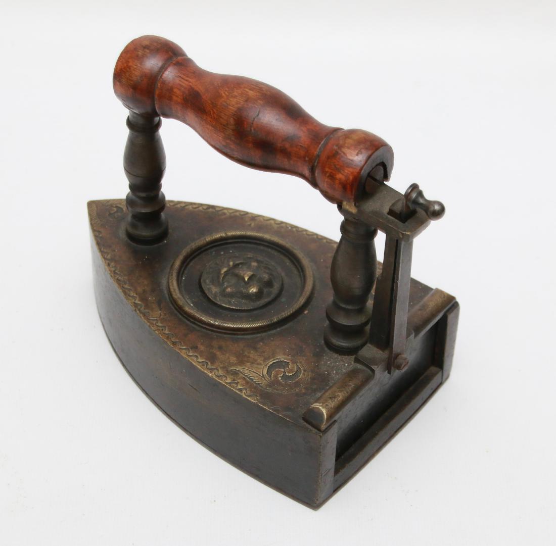 EARLY BRASS SLUG IRON: EMBOSSED LIONS HEAD IN CIRCLE - DOUBLE POST HANDLE - DECORATED EDGE . 7"