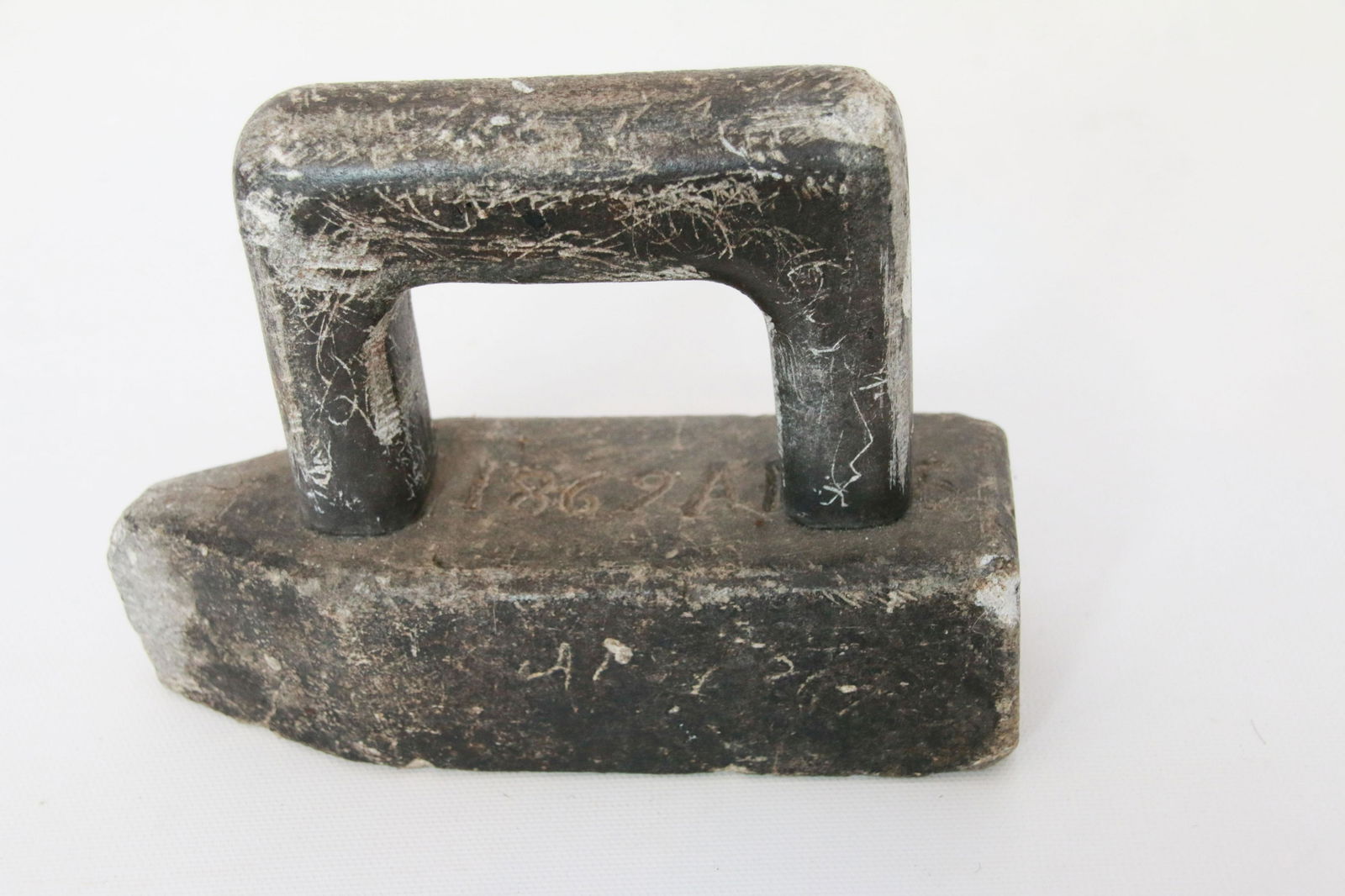 STONE FLAT IRON: DOUBLE DATED STONE IRON - MARKED 1869 ON TOP AND 1904 ON SIDE - IRON HAS MULTIPLE NAMES AND DATES INSCRIBED IN IRON FROM PEOPLE WHO USED Size: 6 1/2"