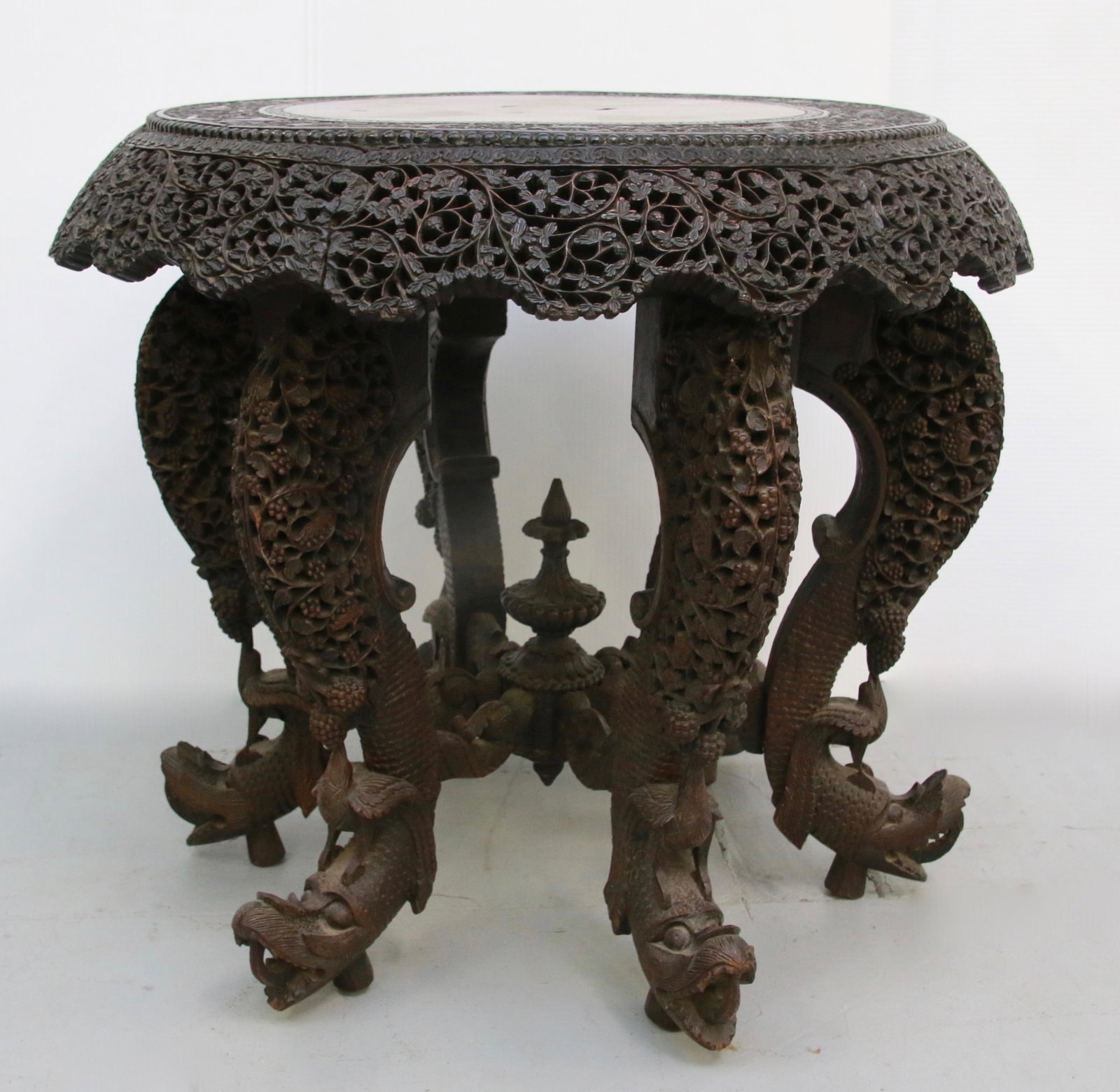 CHINESE TABLE: ROUND CARVED ROSEWOOD CHINESE TABLE WITH ROTATING TOP ON BRASS ROLLERS - ORNATE CARVING OF VINES - BIRDS AND DRAGON HEADS ON 6 LEGS Size: 22.5" X 26" DIAMETER