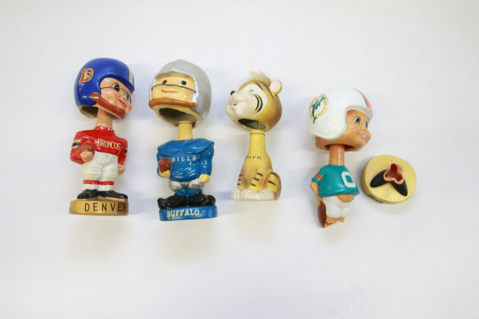GROUP LOT OF FOOTBALL BOBBLE HEAD FIGURES: FOUR INCLUDING: DENVER BRONCOS MRKD. JAPAN, BUFFALO BILLS MRKD. JAPAN, AUBURN TIGER MRKD. JAPAN, MIAMI DOLPHINS, 1975 TAIWAN. 6" TO 7" H
