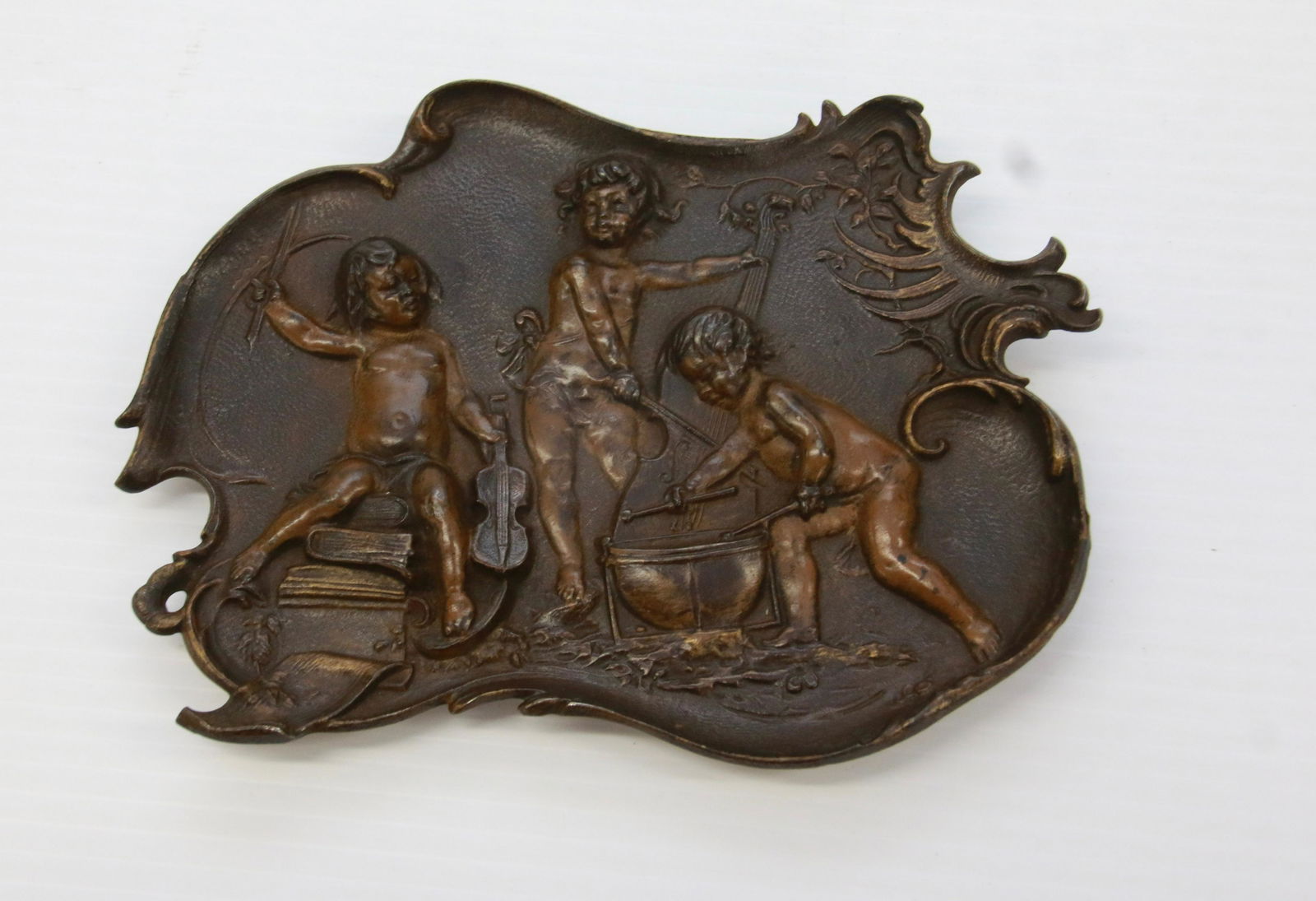 CAST IRON TRAY DEPICTING MUSIC MAKERS: HANG HOOK AND FEET ON BACK. 8" X 5 1/2"