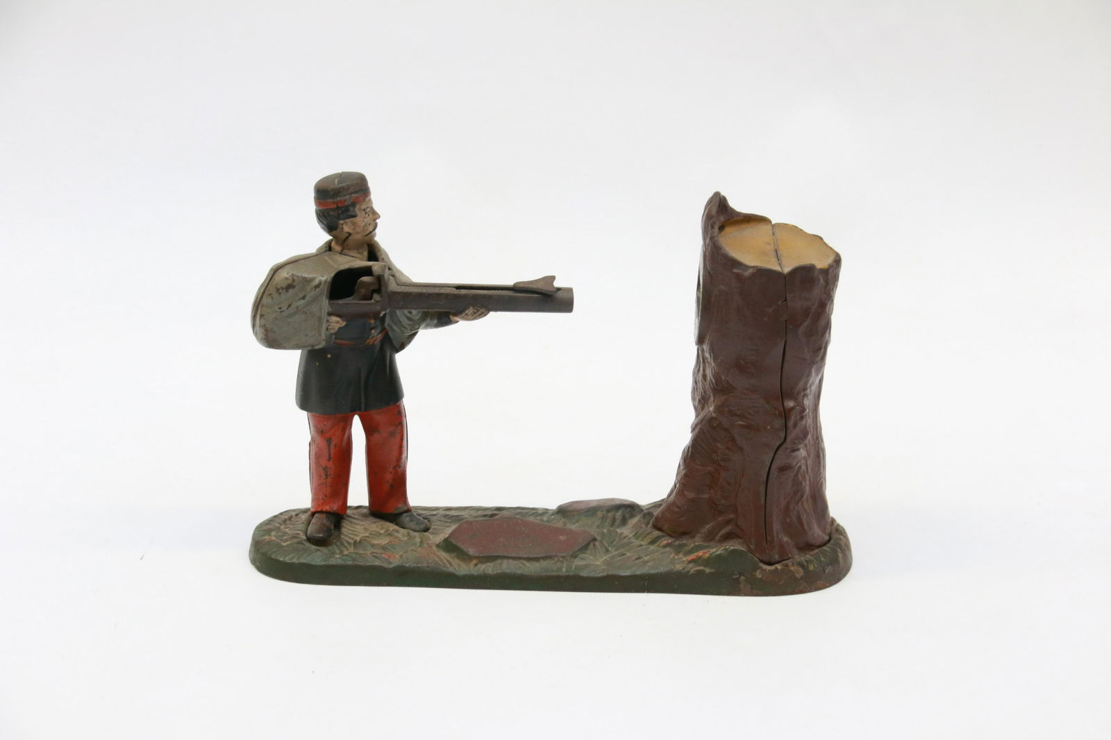 CREEDMORE MECHANICAL BANK: PAINTED CAST IRON. SHOOTER WITH TREE TRUNK TARGET. 10" X 6 3/4" H