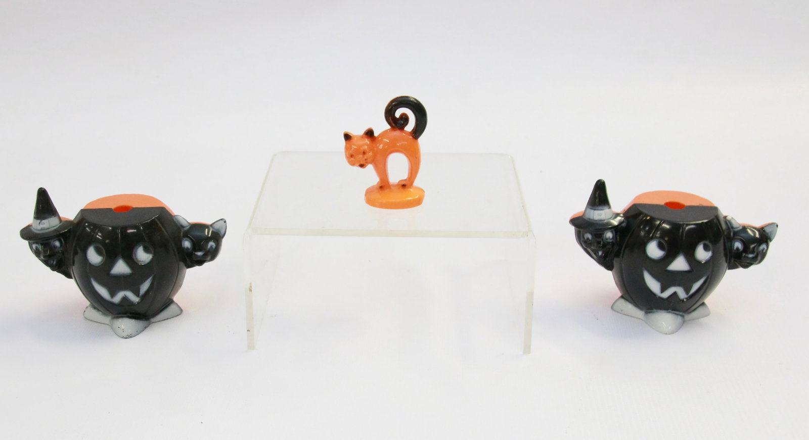 GROUP LOT OF HALLOWEEN NOVELTIES: THREE INCLUDING: PAIR OF PLASTIC BLACK AND ORANGE PUMPKIN/WITCH/CAT AND ORANGE/BLACK PLASTIC CAT Size: PUMPKINS MEASURE 4" ACROSS AND CAT IS 1 1/4" HEIGHT.