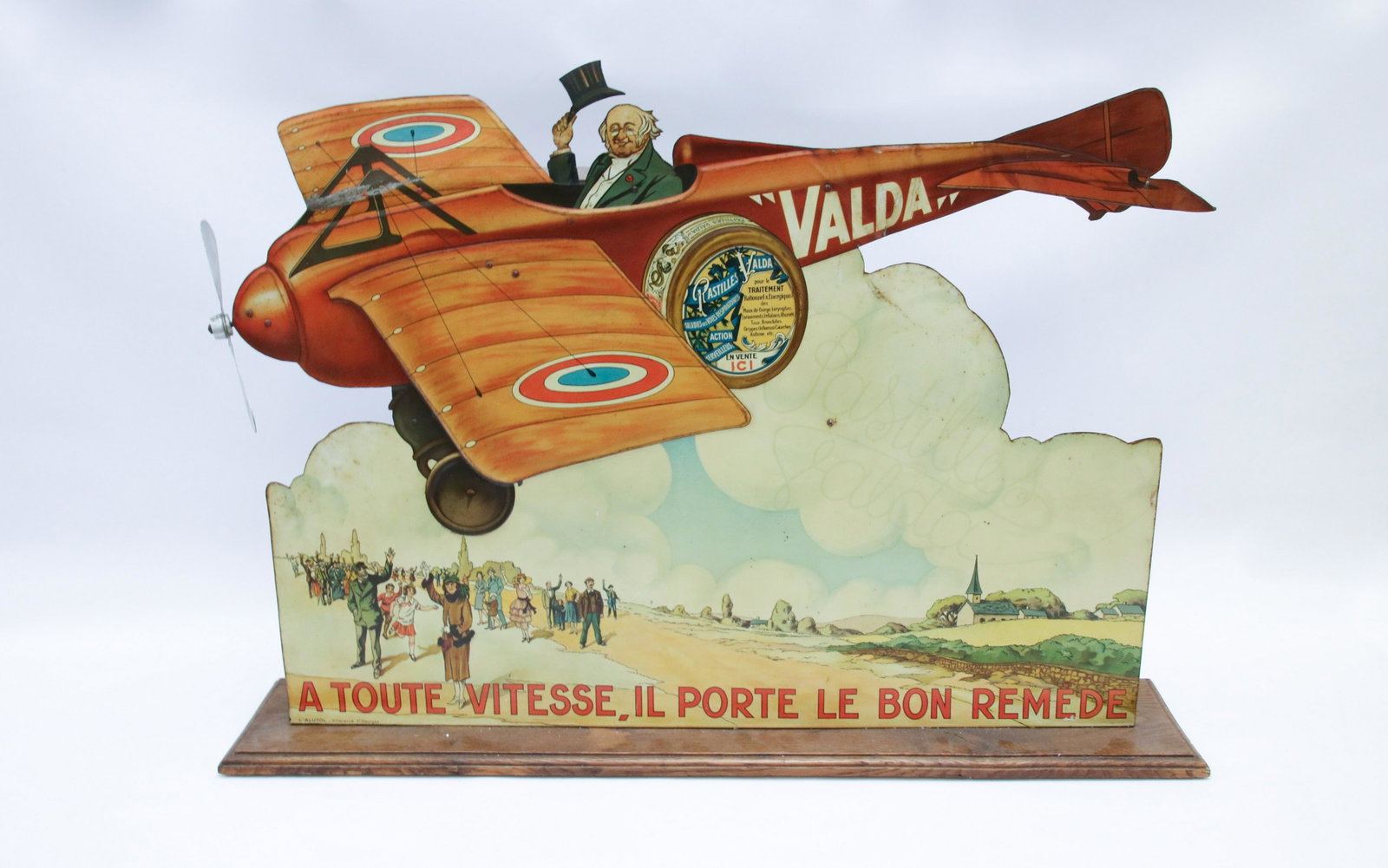 1930'S PHARMACY ADVERTISING AUTOMATON: ADVERTISING PASTILLES VALDA - IN THE FORM AN AIRPLANE WITH GENTLEMAN WAVING TOP HAT - LITHOGRAPHED SHEET IRON, FRANCE 1930 - WIND UP MECHANISM Size: 25" H X 31 1/2" W X 7" D We do not give IN-HOUSE sh