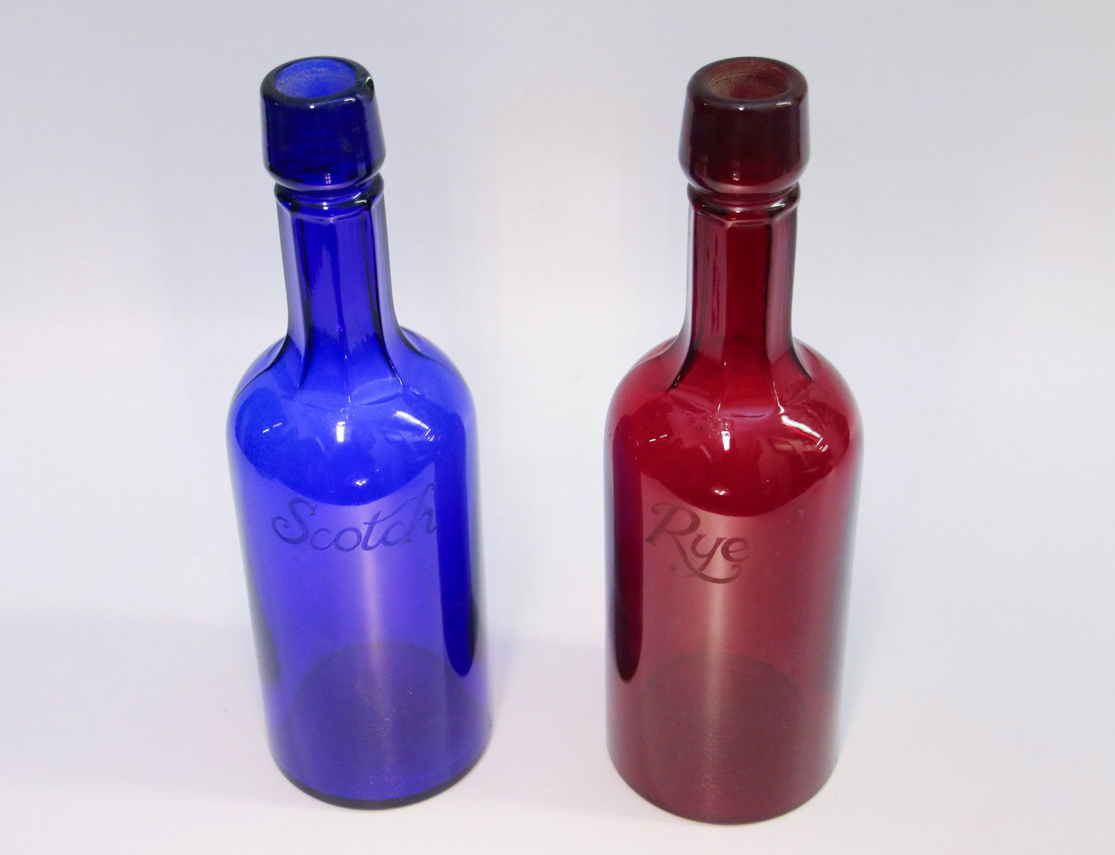 PAIR OF COLORED BAR BOTTLES: RUBY RED "RYE". COBALT BLUE "SCOTCH" Dimensions: 11" H