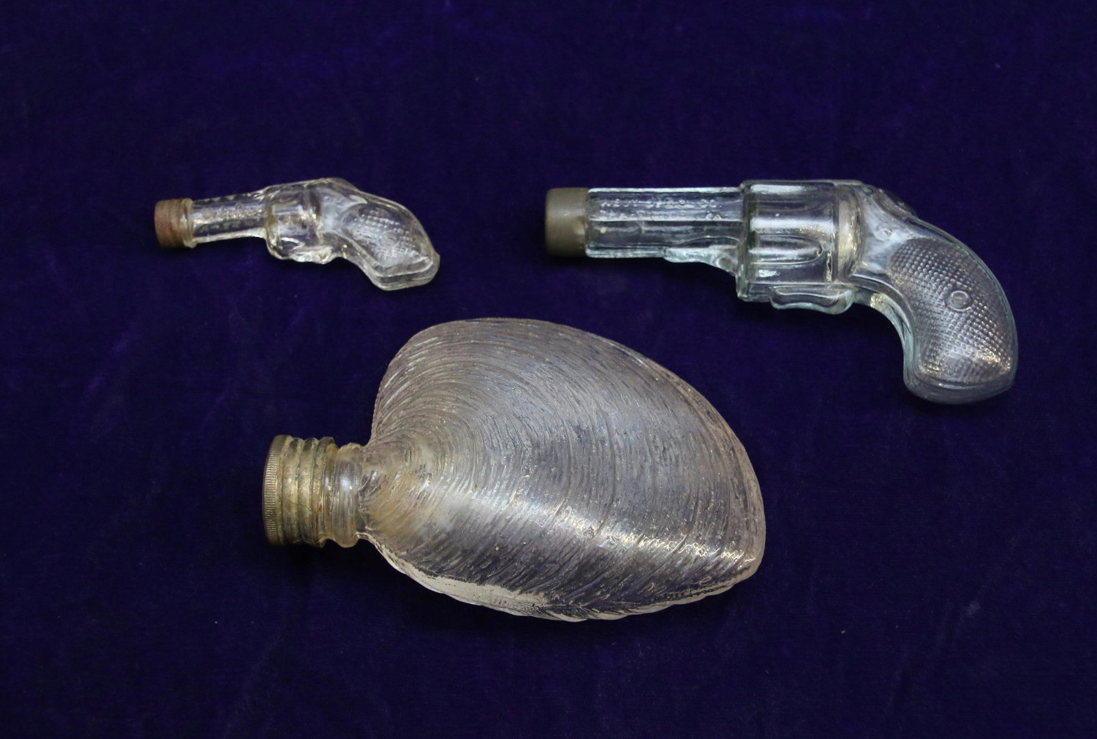 GROUP LOT OF FIGURAL FLASKS: INCLUDES: LIGHT GREEN REVOLVER "WEST SPECIALTIES CO.", MINI REVOLVER "W.C.CO." AND CLAM SHELL. Dimensions: 3 1/2" TO 5 1/2"