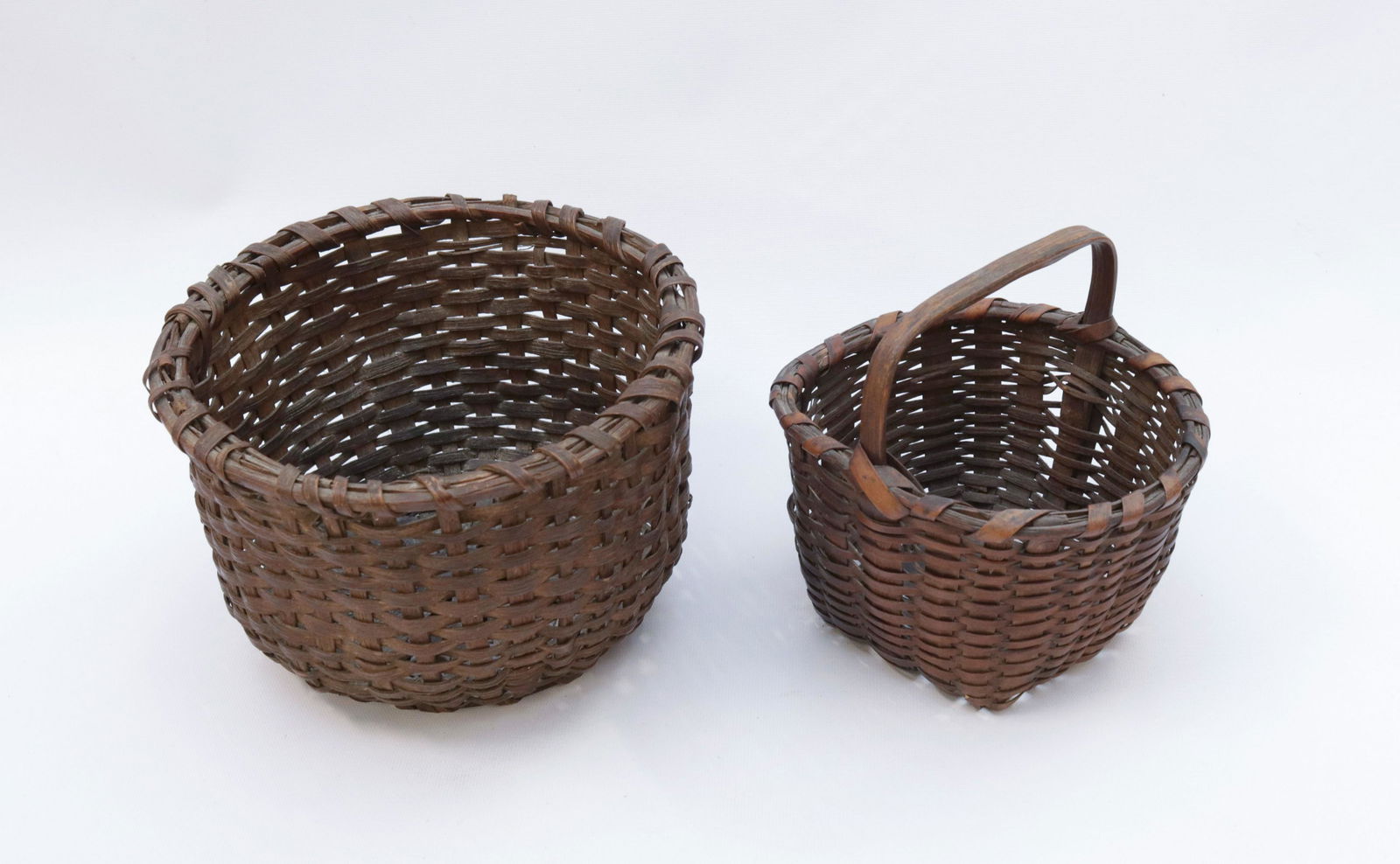 PR. OF SMALL GATHERING BASKETS: (2) HAND WOVEN BASKETS - ONE WITH HANDLE - NEW JERSEY ORIGINS 6 3/4" X 7" X 6 1/2" - 6" X 9 1/2" X 8 3/4"