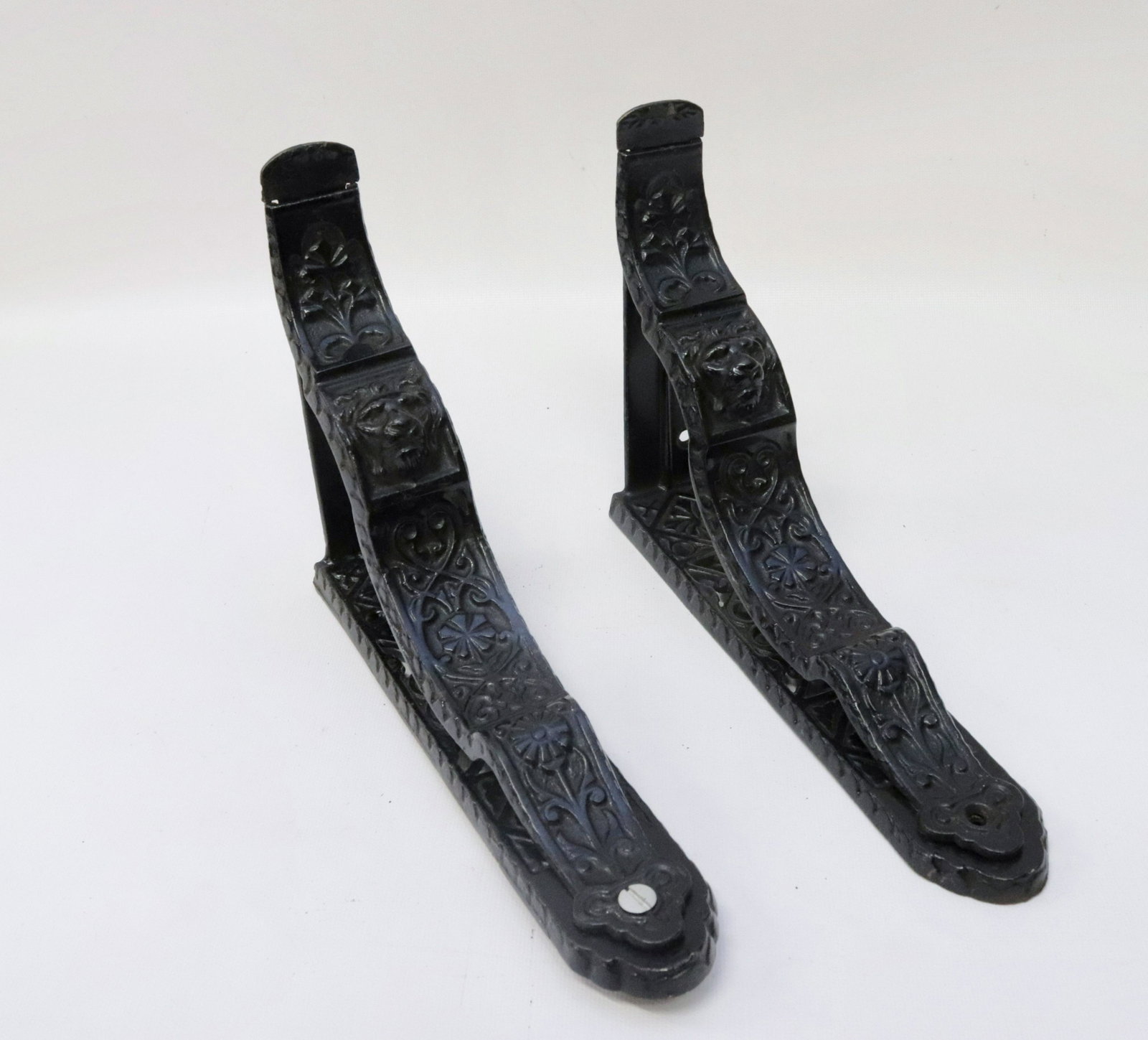 PAIR OF CAST IRON SHELF BRACKETS: UNUSUAL FORM. LION HEADS 9 1/2" X 6 3/4"